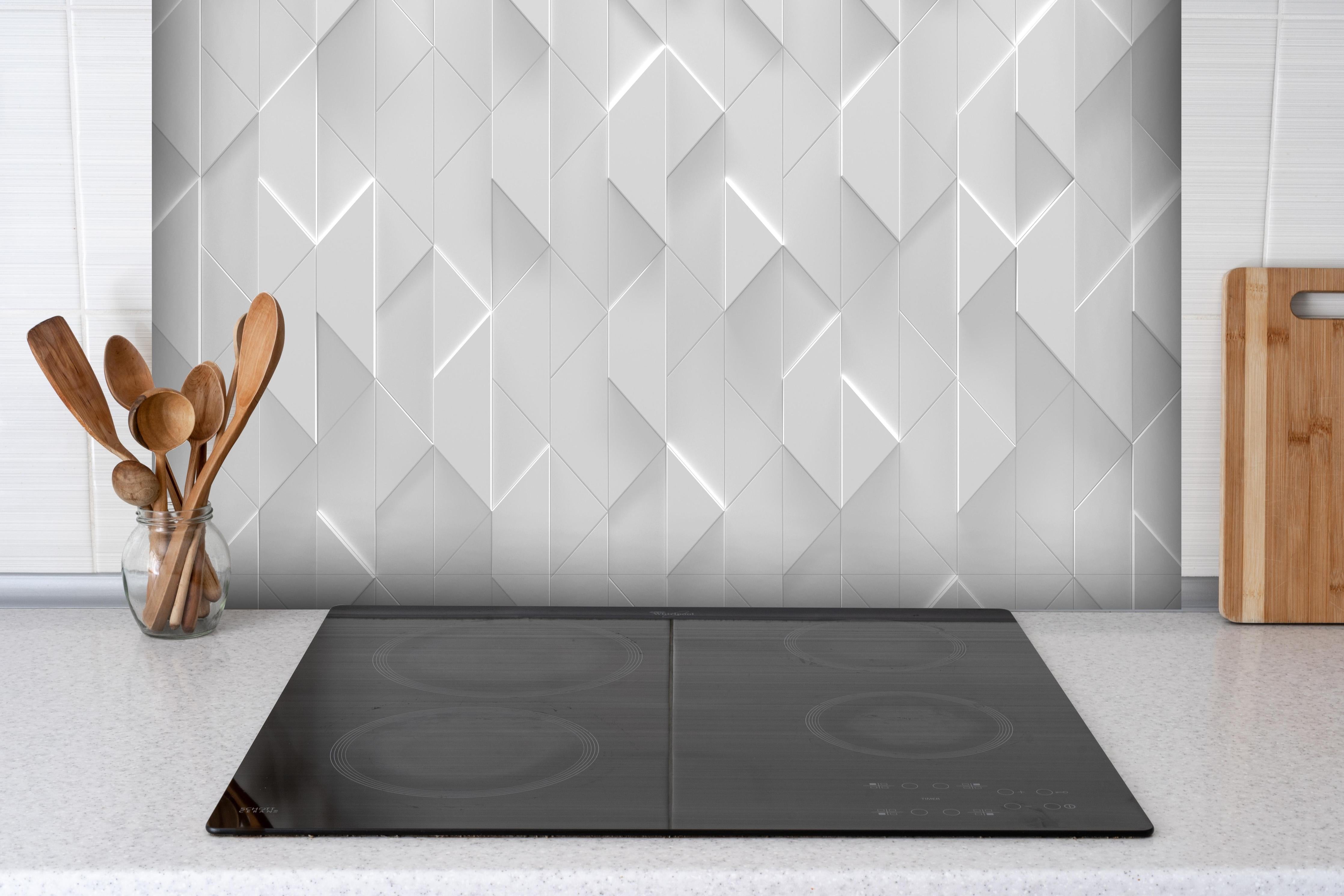 Spritzschutz - Futuristische Zigzag-Struktur in Weiß-Grau hinter einem Cerankochfeld zwischen Holz-Kochutensilien