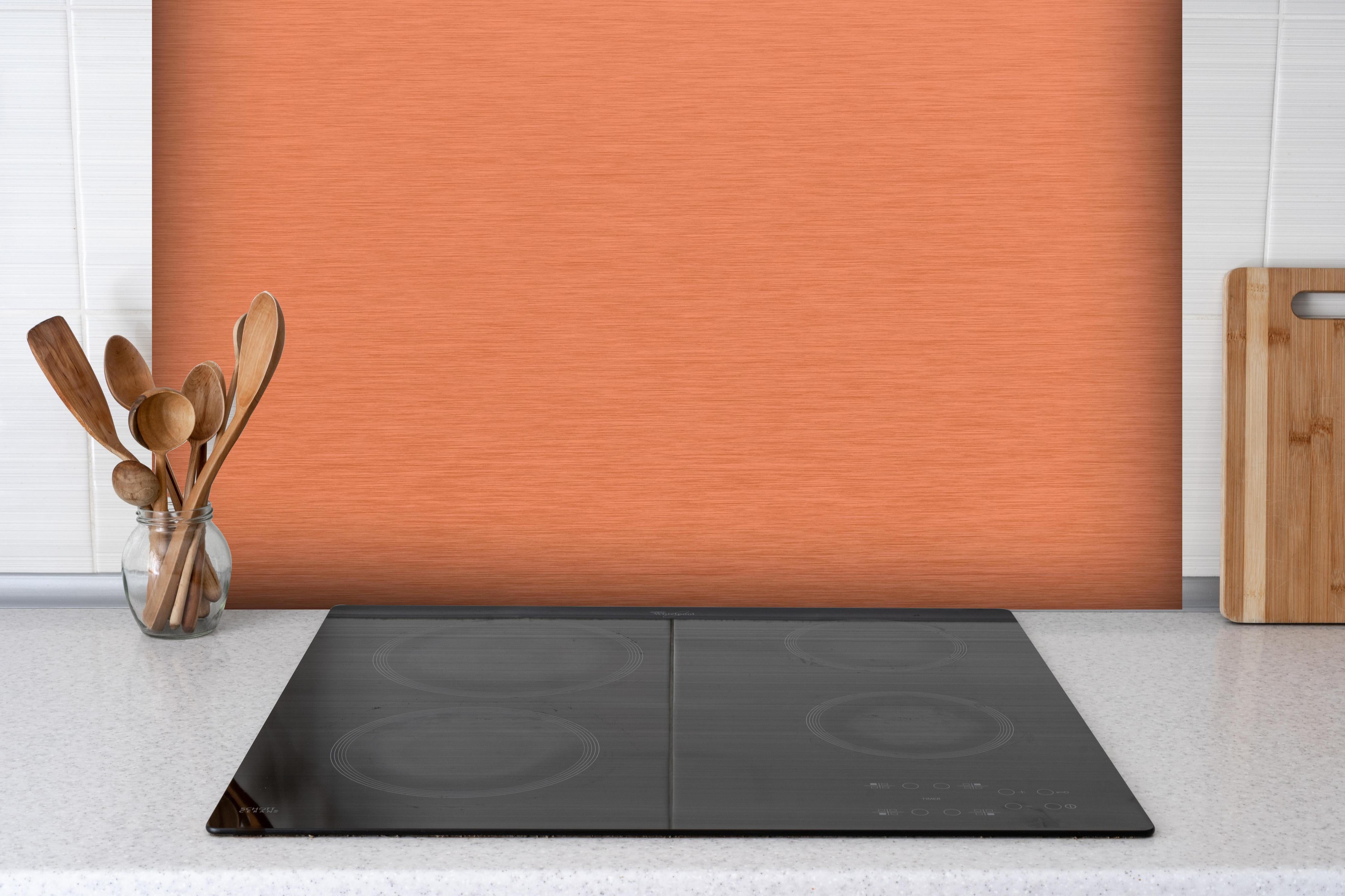 Spritzschutz - Gebürstete Kupfertextur mit Metalloptik hinter einem Cerankochfeld zwischen Holz-Kochutensilien