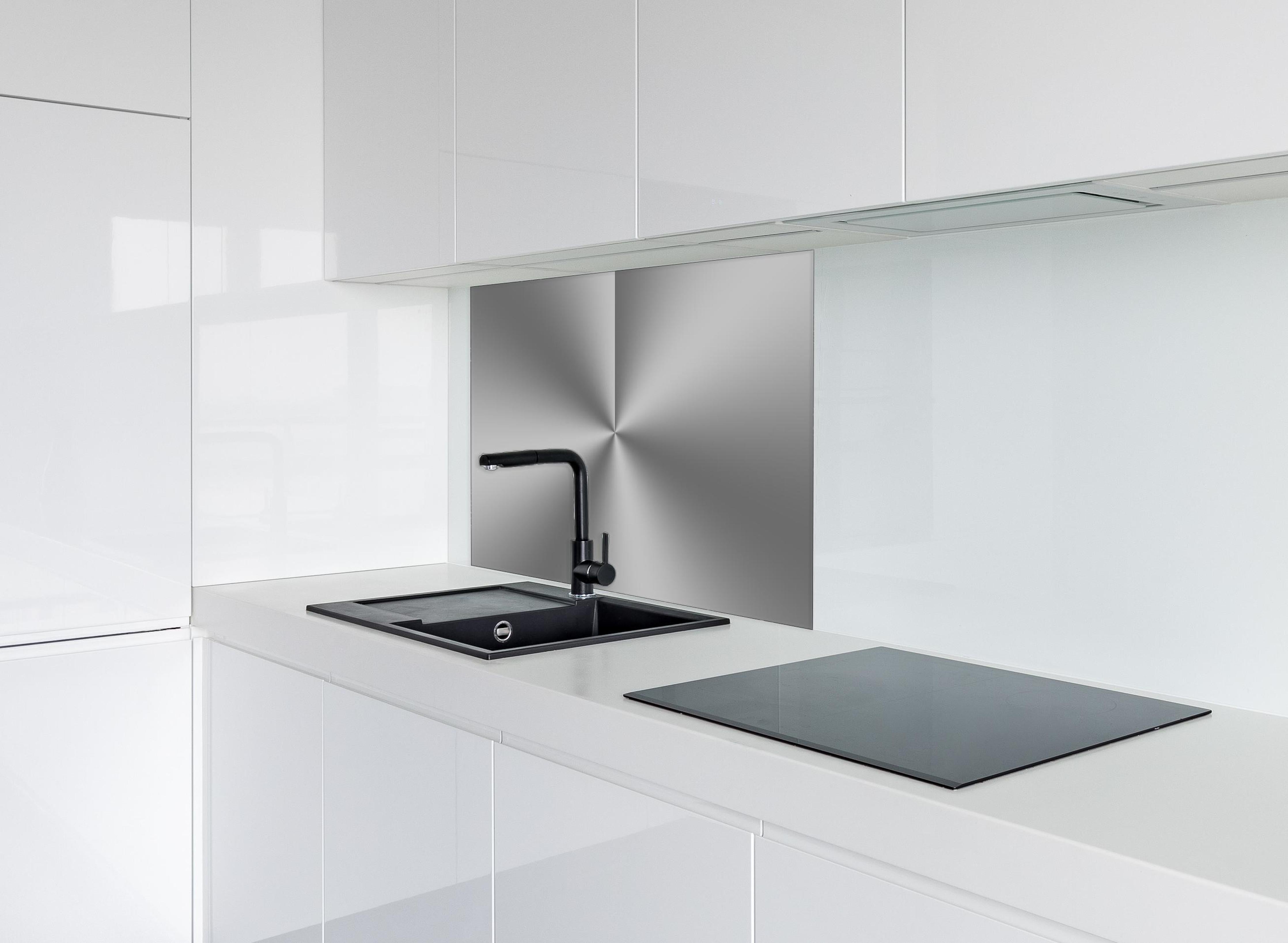 Spritzschutz - Gebürstetes Metall hinter einem Cerankochfeld zwischen Holz-Kochutensilien