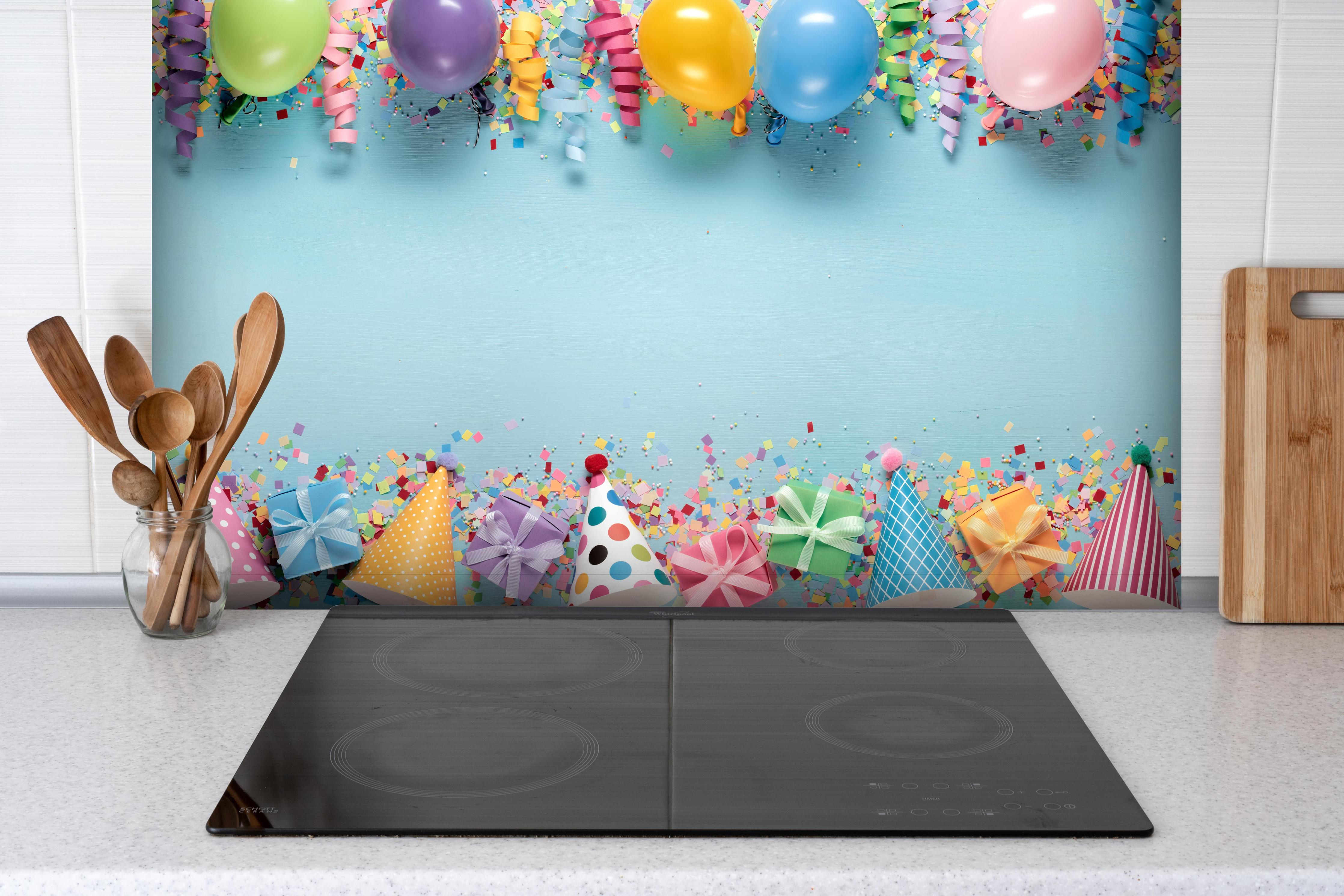 Spritzschutz - Geburtstagsfeier Dekoration hinter einem Cerankochfeld zwischen Holz-Kochutensilien