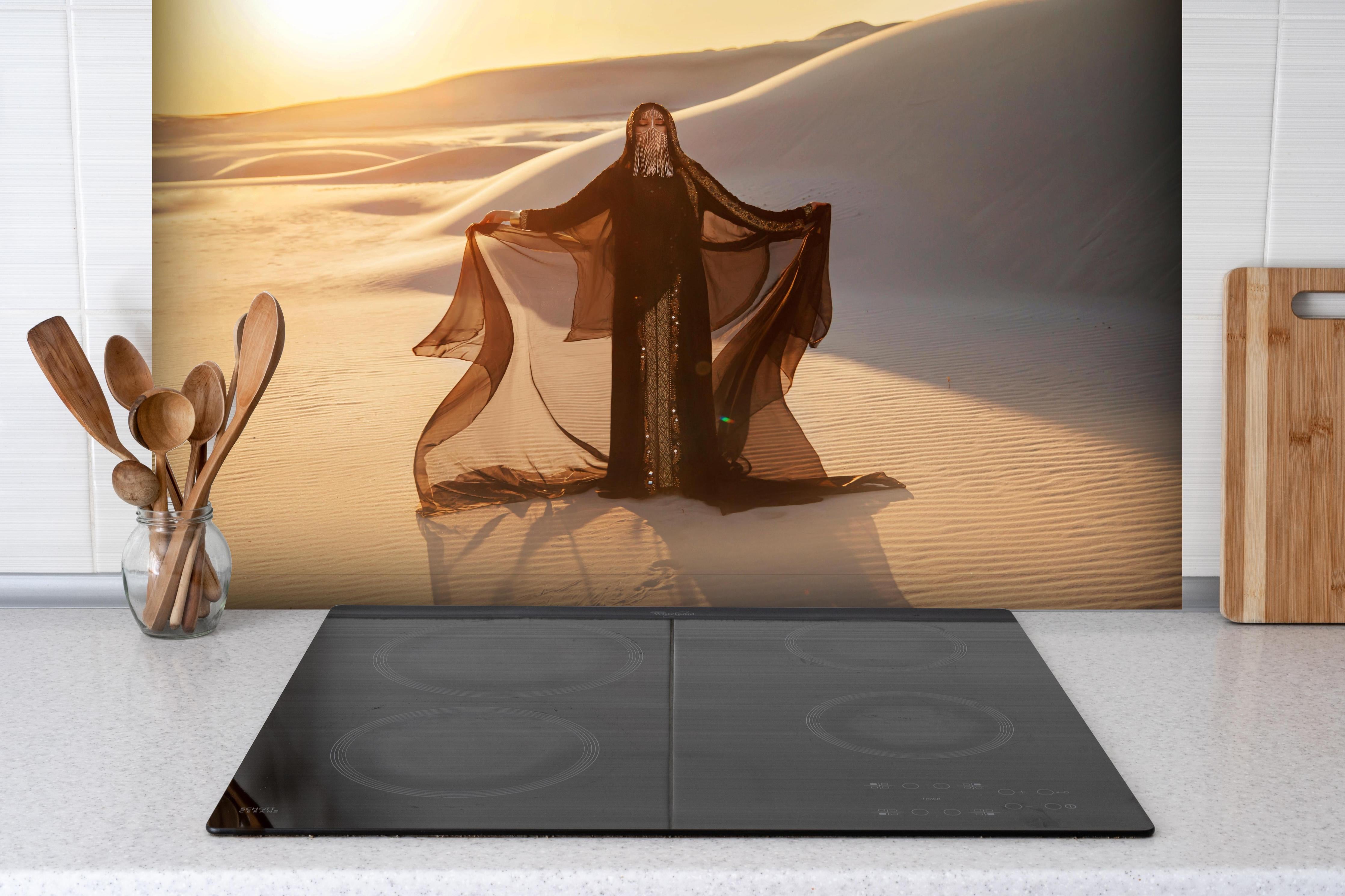 Spritzschutz - Geheimnisvolle Frau steht in arabischer Savanne hinter einem Cerankochfeld zwischen Holz-Kochutensilien