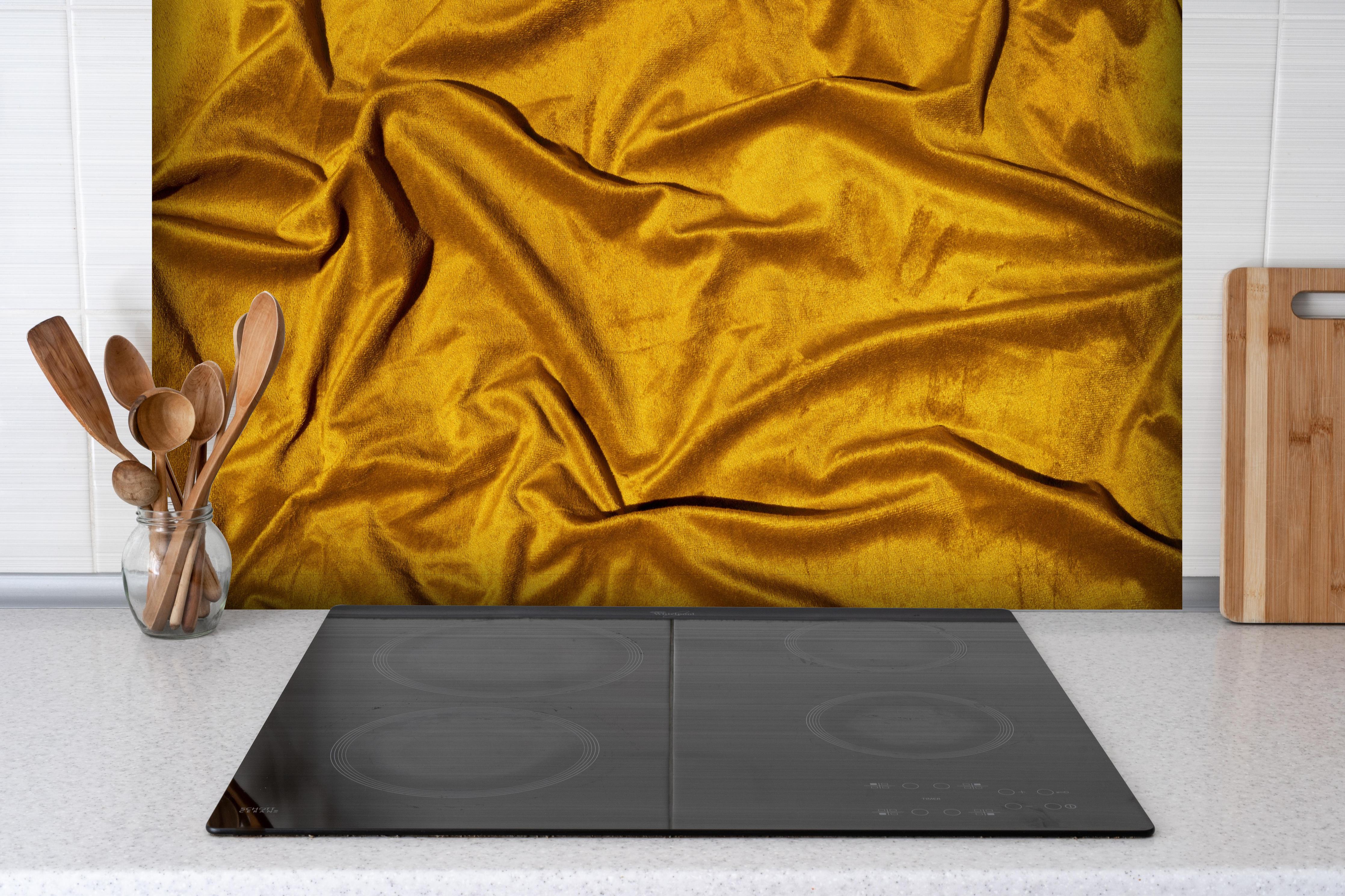 Spritzschutz - Gelbe Satin Seide hinter einem Cerankochfeld zwischen Holz-Kochutensilien