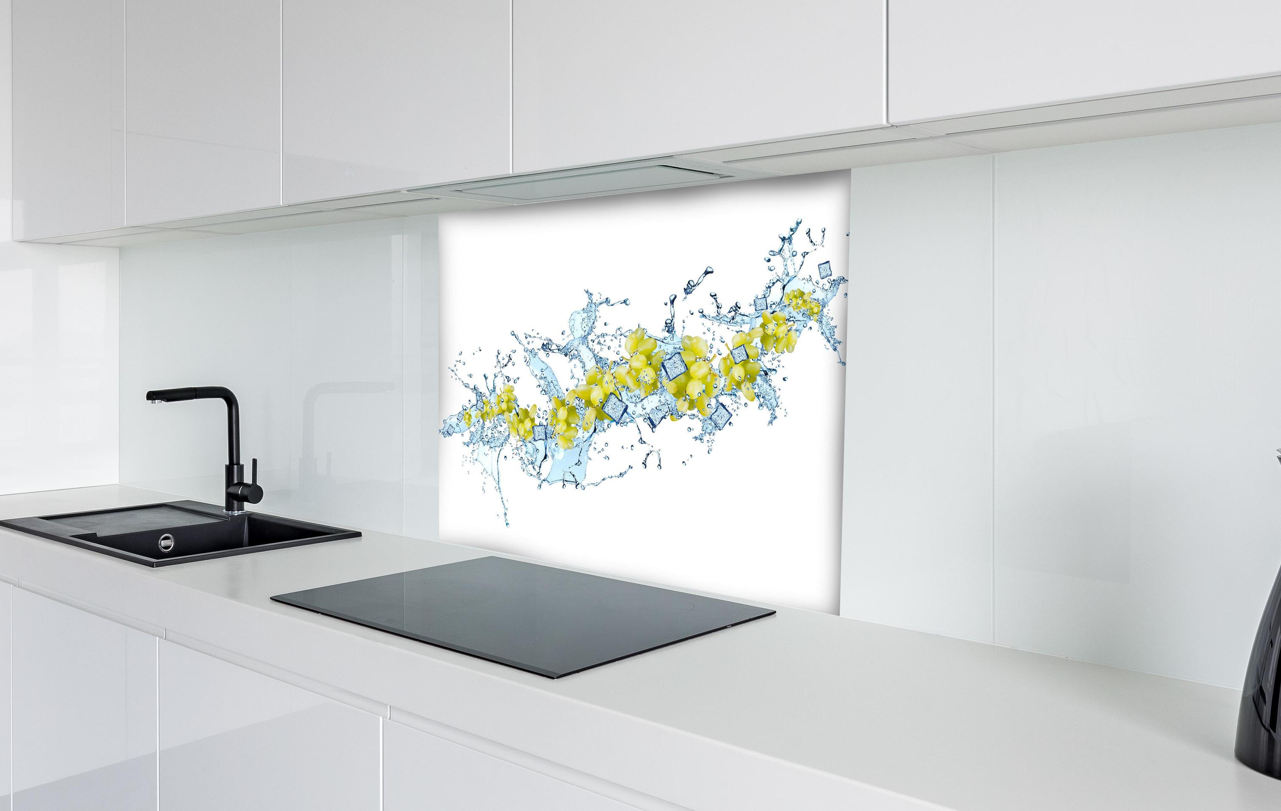 Spritzschutz - Gelbe Trauben mit dynamischem Wasser Splash hinter einem Cerankochfeld zwischen Holz-Kochutensilien