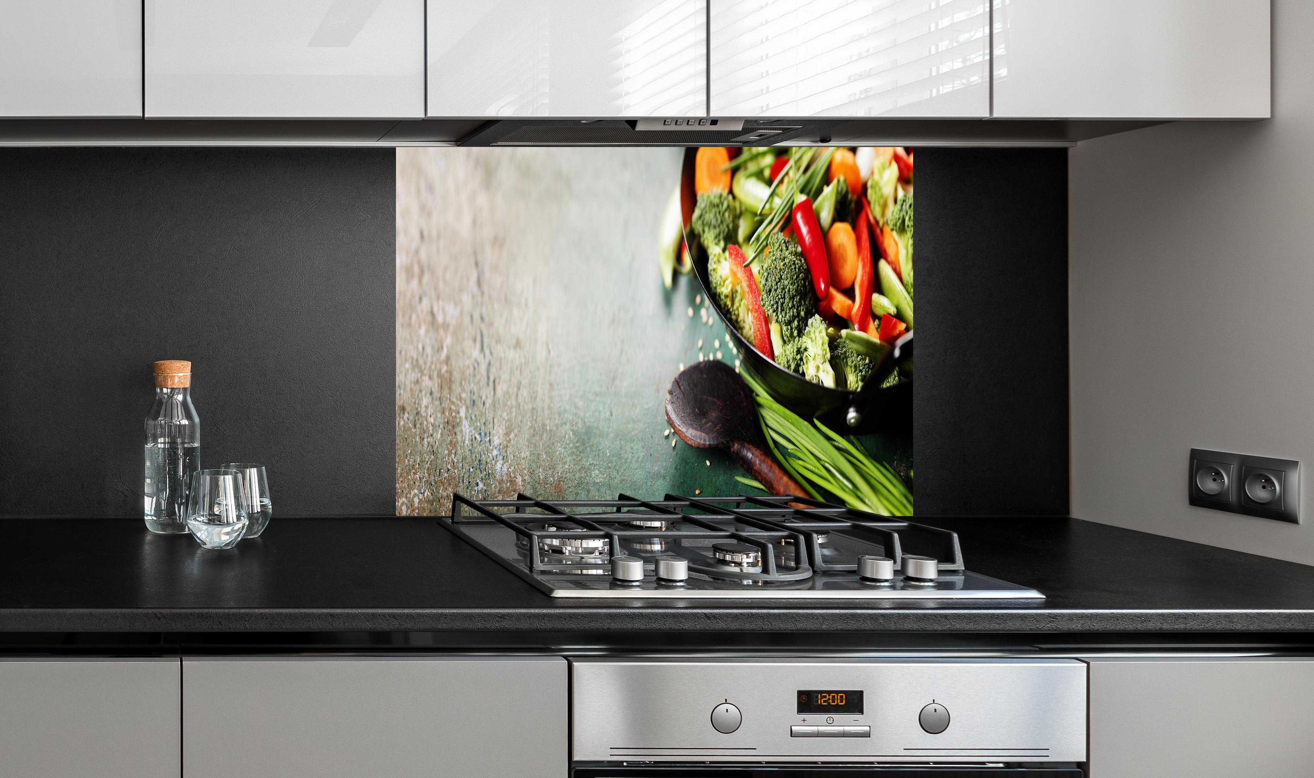 Spritzschutz - Gemüse kochen im Wok hinter einem Cerankochfeld zwischen Holz-Kochutensilien