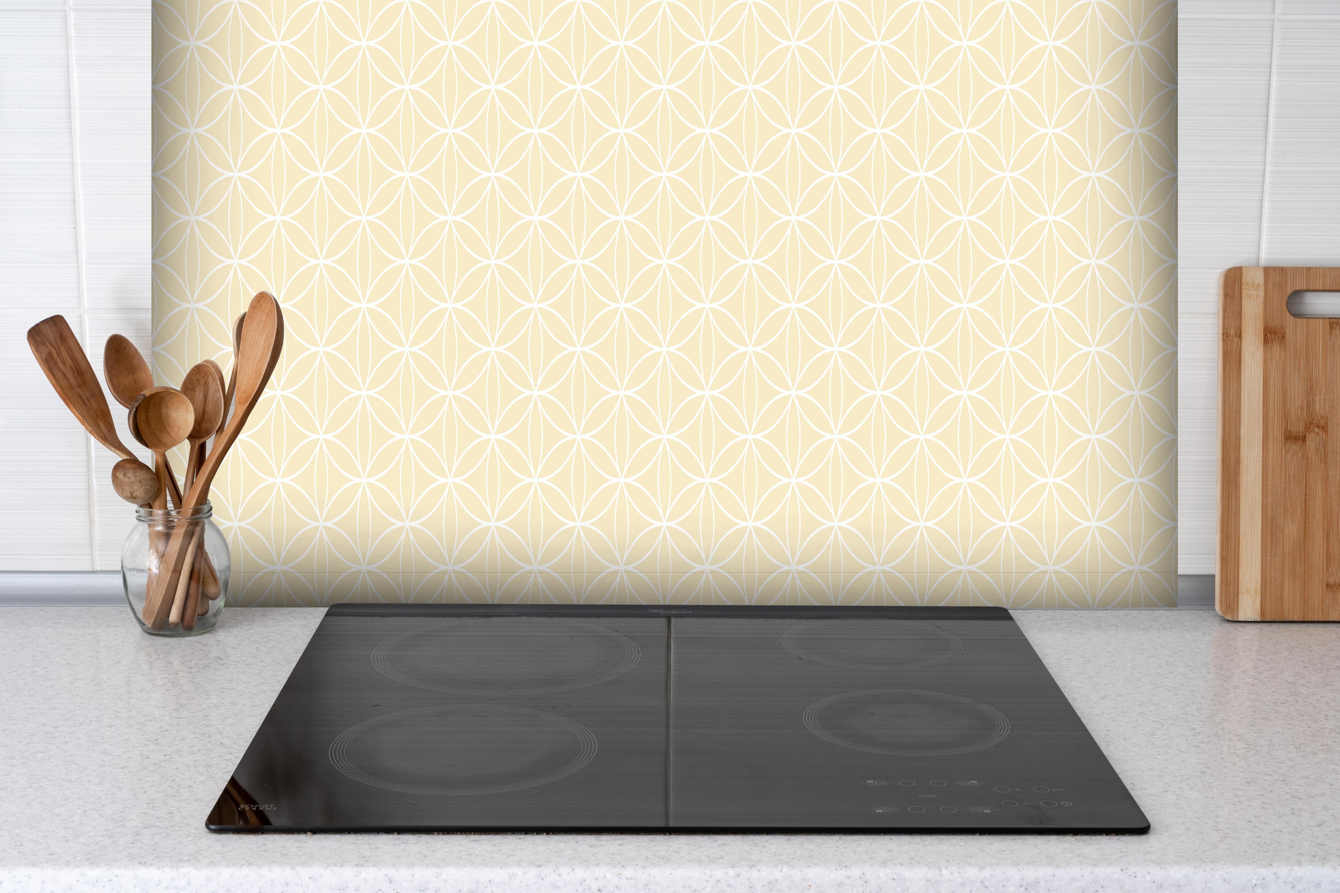 Spritzschutz - Geometrica Fiori Avorio hinter einem Cerankochfeld zwischen Holz-Kochutensilien
