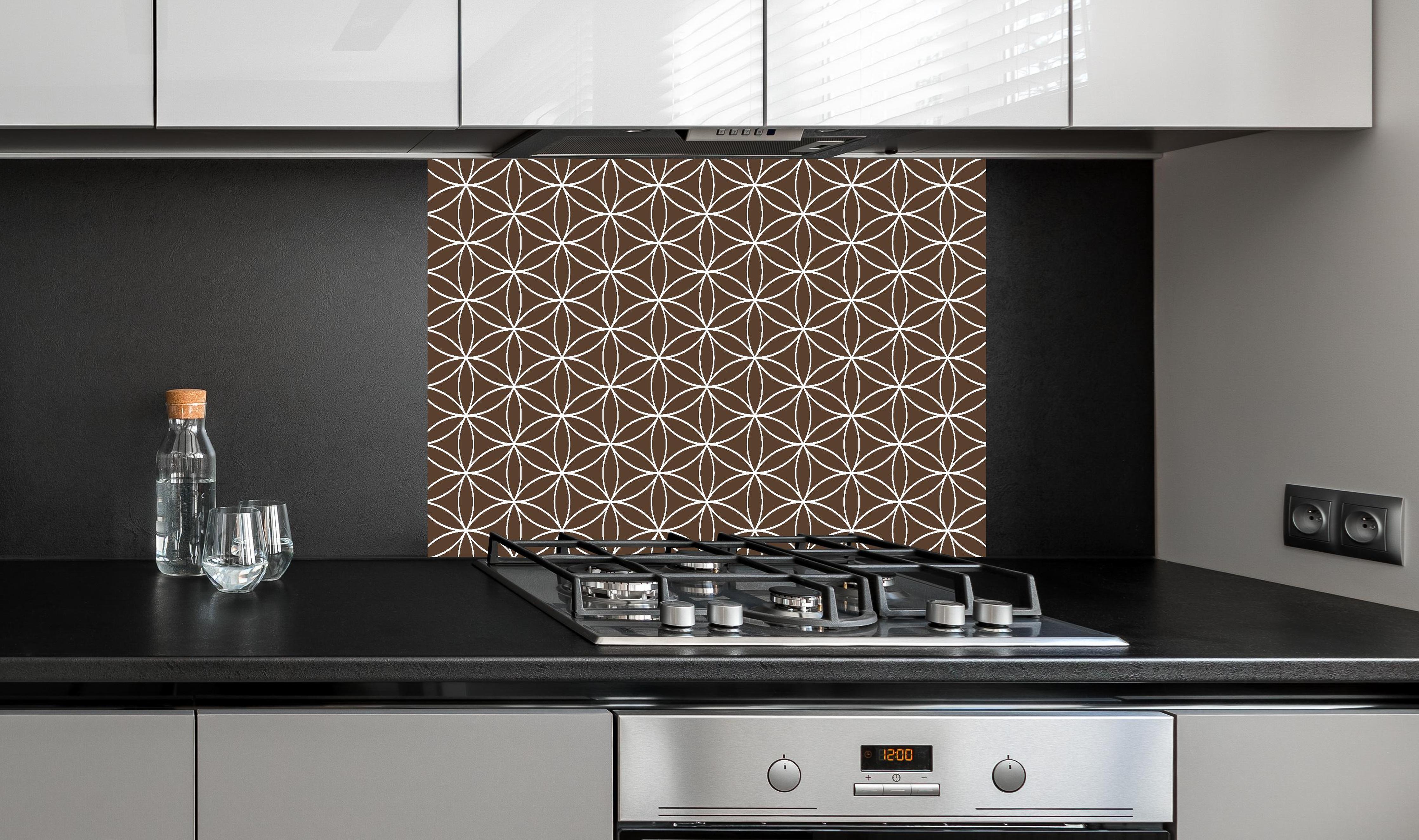 Spritzschutz - Geometrica Fiori Caffè hinter einem Cerankochfeld zwischen Holz-Kochutensilien