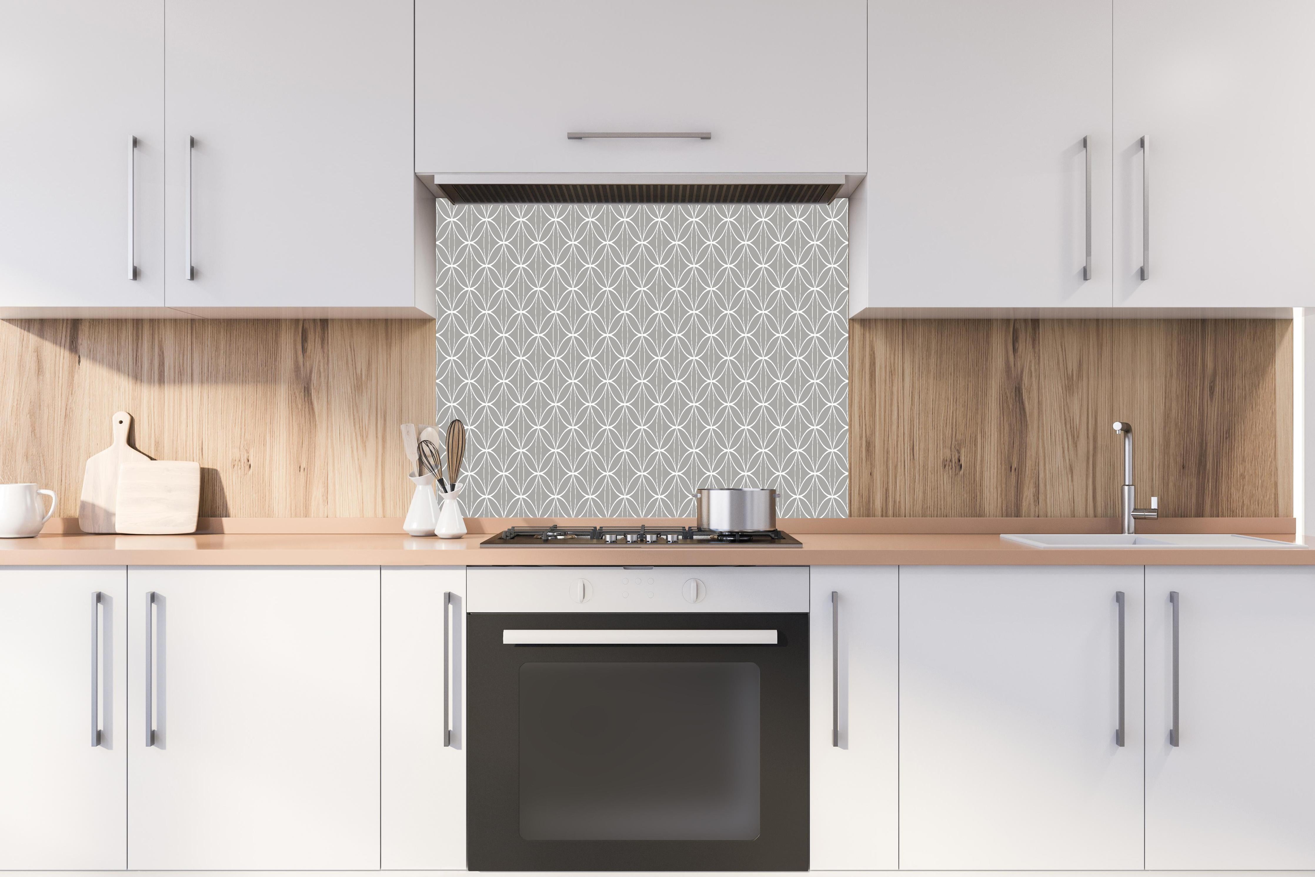 Spritzschutz - Geometrica Fiori Cemento hinter einem Cerankochfeld zwischen Holz-Kochutensilien