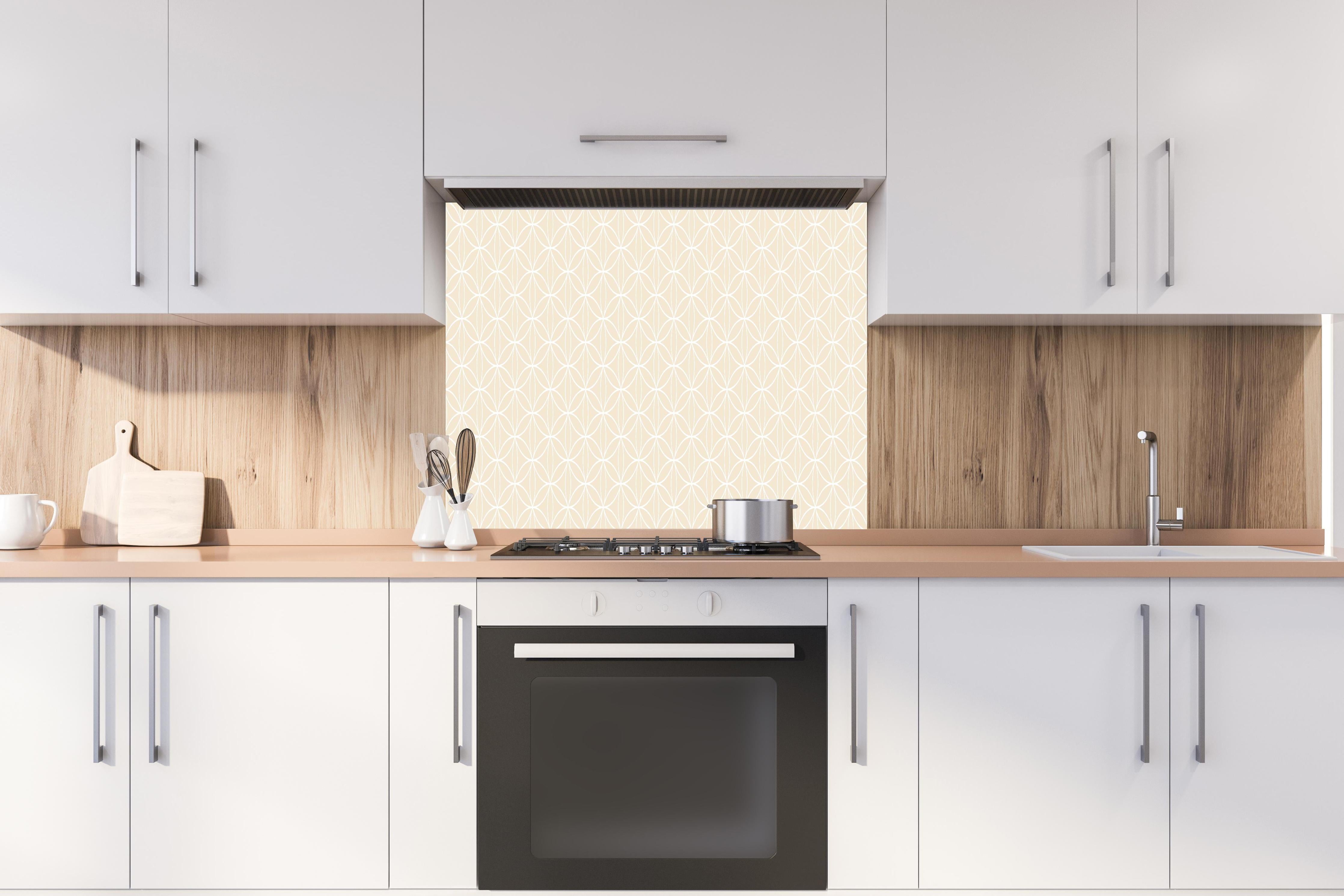 Spritzschutz - Geometrica Fiori Crema hinter einem Cerankochfeld zwischen Holz-Kochutensilien