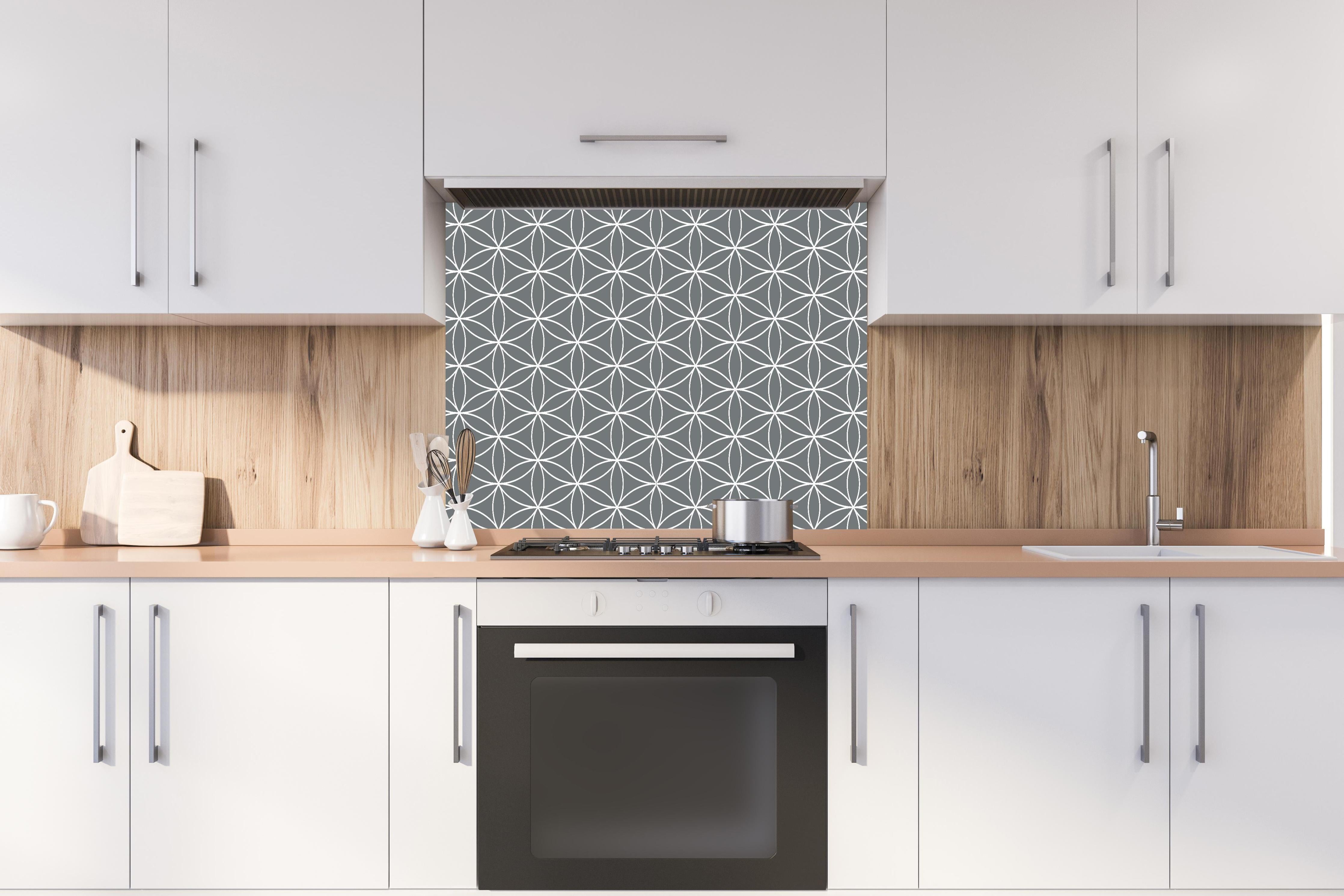 Spritzschutz - Geometrica Fiori Piombo hinter einem Cerankochfeld zwischen Holz-Kochutensilien