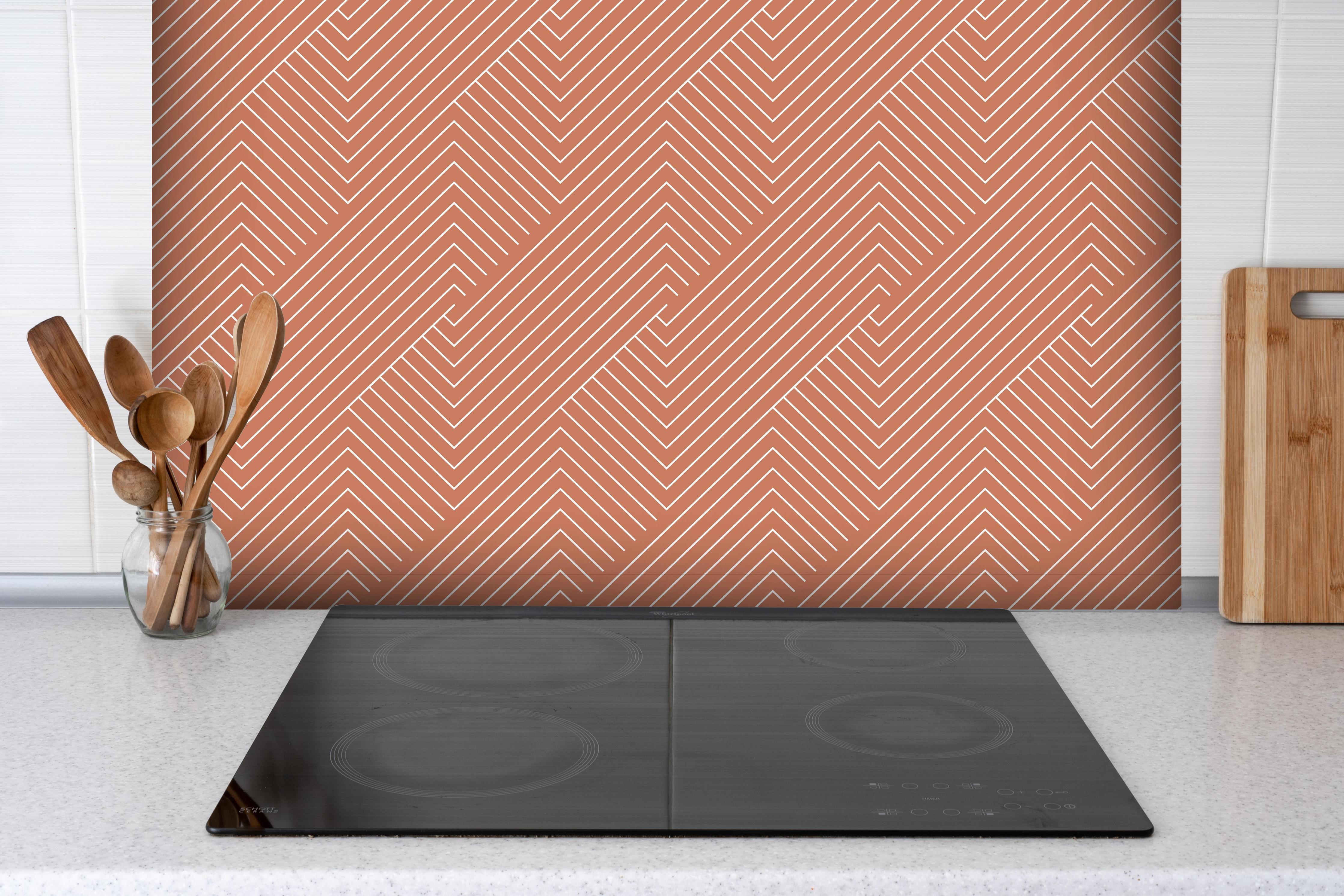 Spritzschutz - Geometrica Intreccio Terracotta hinter einem Cerankochfeld zwischen Holz-Kochutensilien
