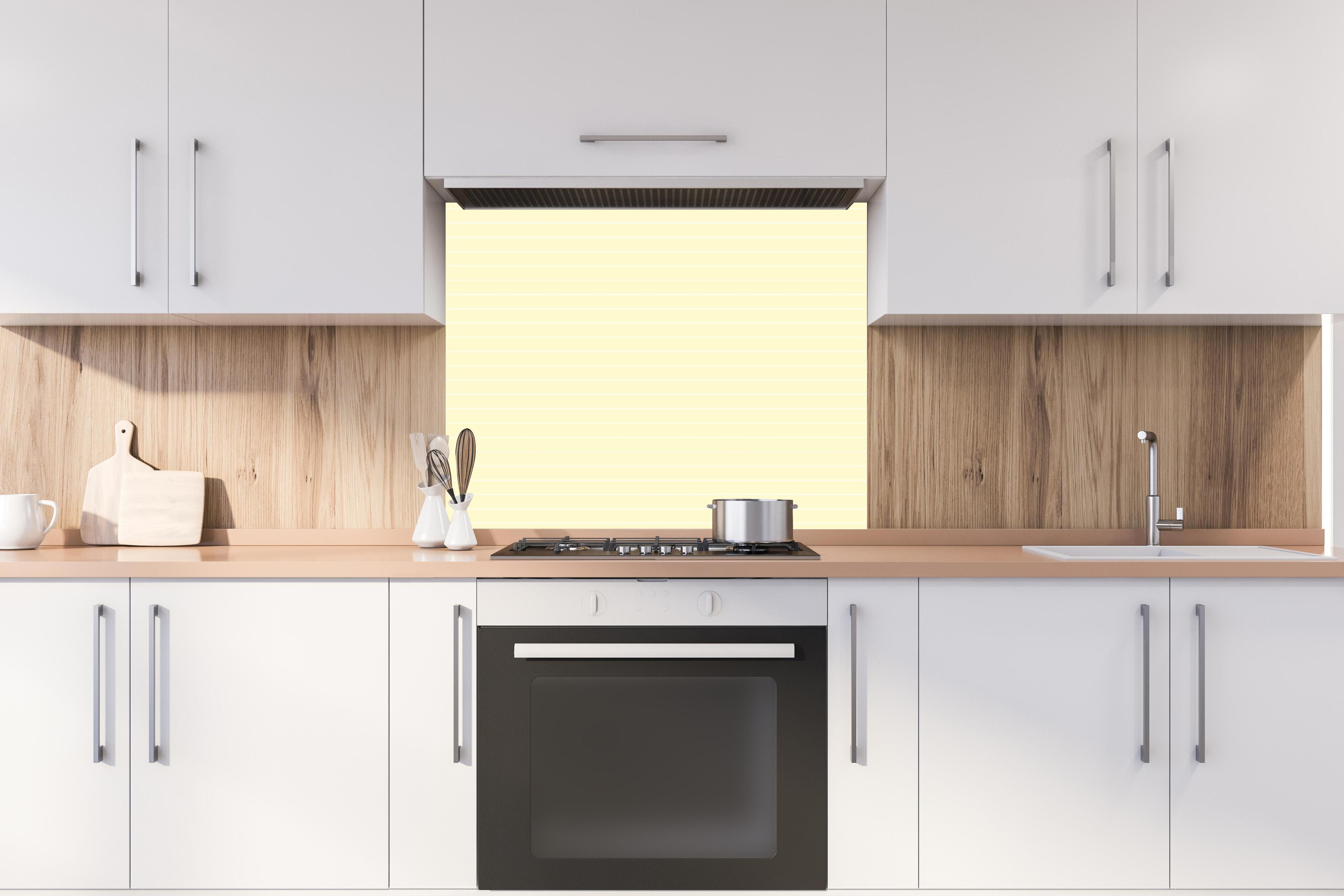 Spritzschutz - Geometrica Orizzontale Limone crema hinter einem Cerankochfeld zwischen Holz-Kochutensilien