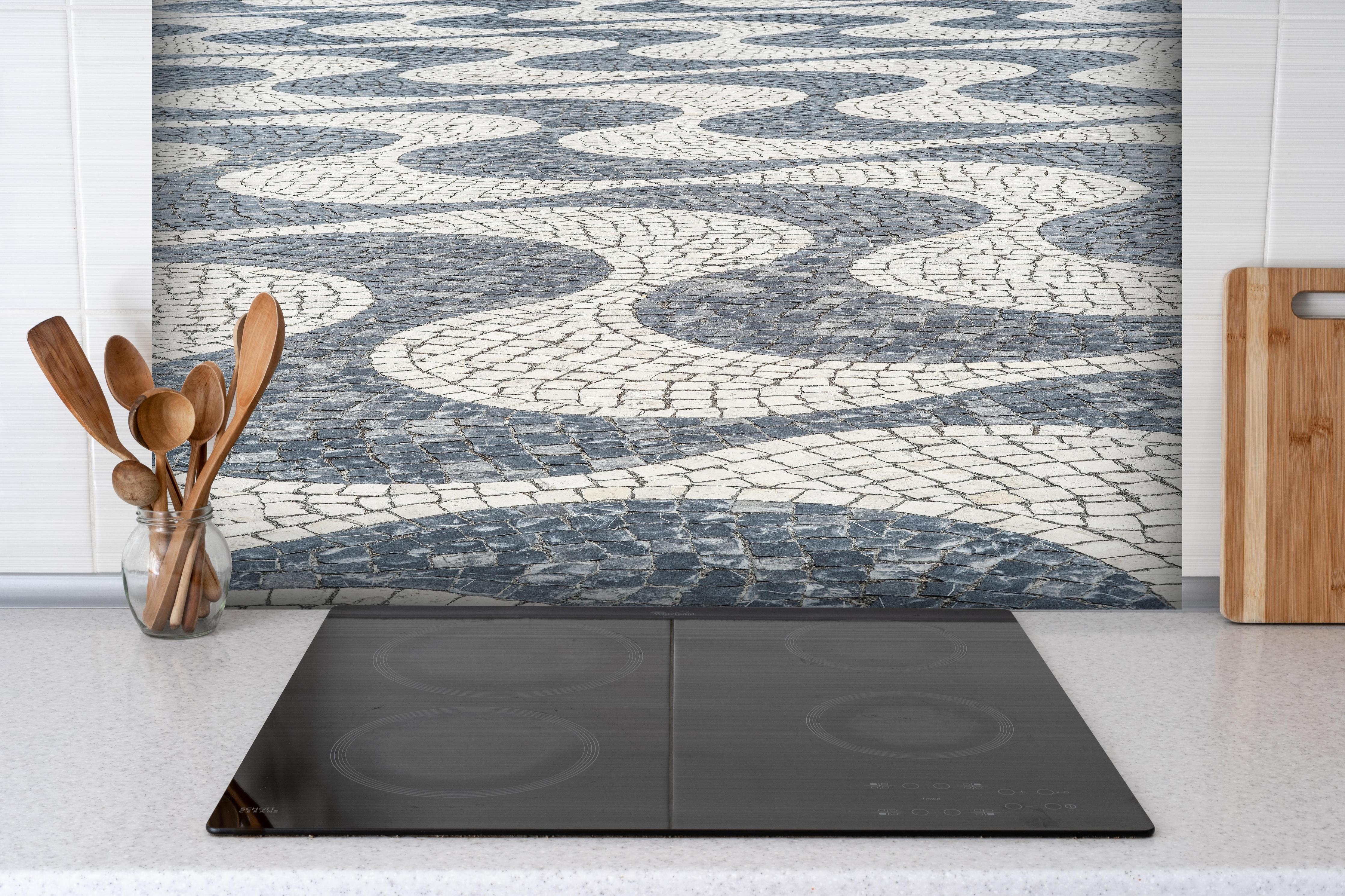 Spritzschutz - Geometrisches Mosaikmuster in Schwarz-Weiß hinter einem Cerankochfeld zwischen Holz-Kochutensilien