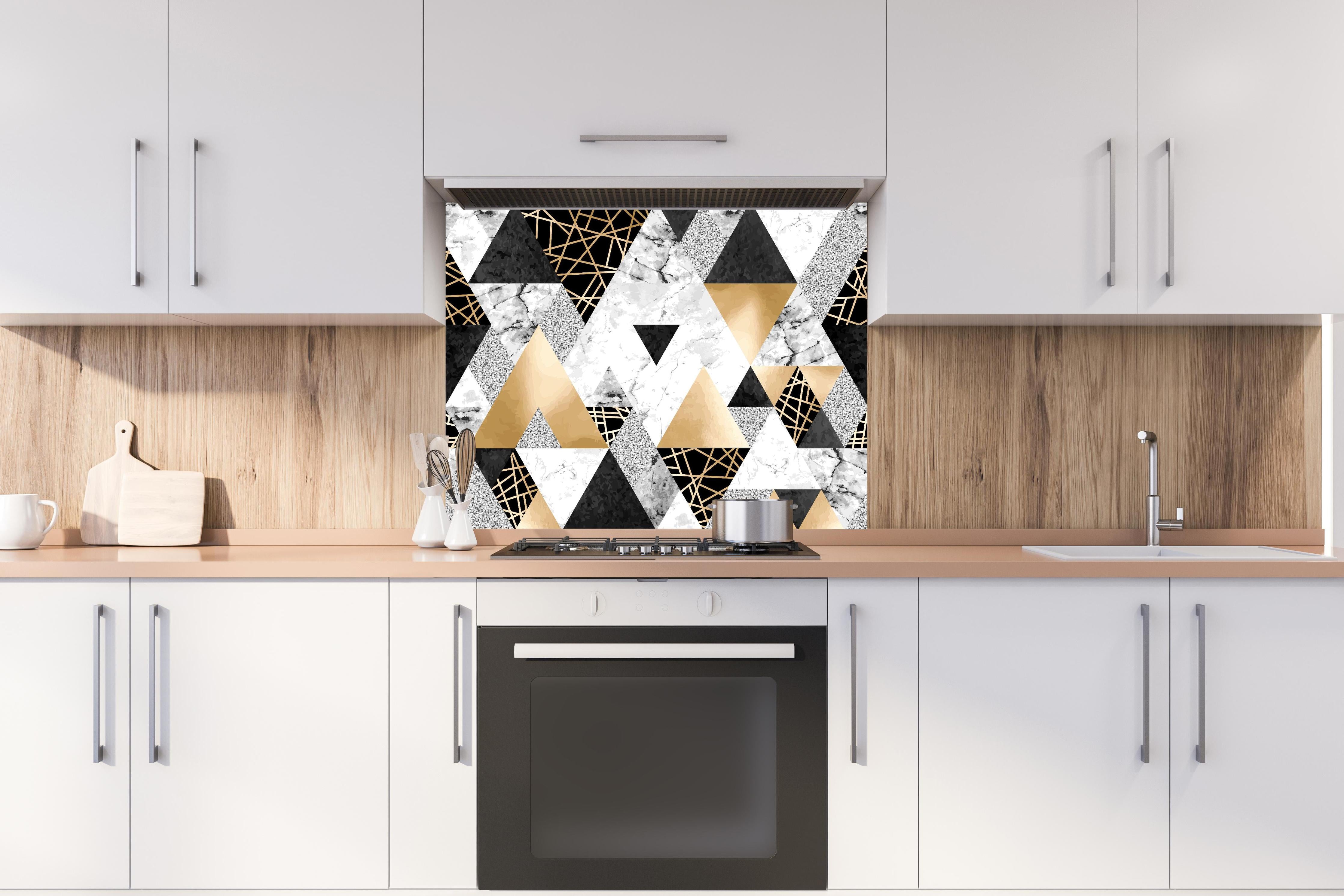 Spritzschutz - Geometrisches Muster in Gold, Schwarz und Weiß hinter einem Cerankochfeld zwischen Holz-Kochutensilien
