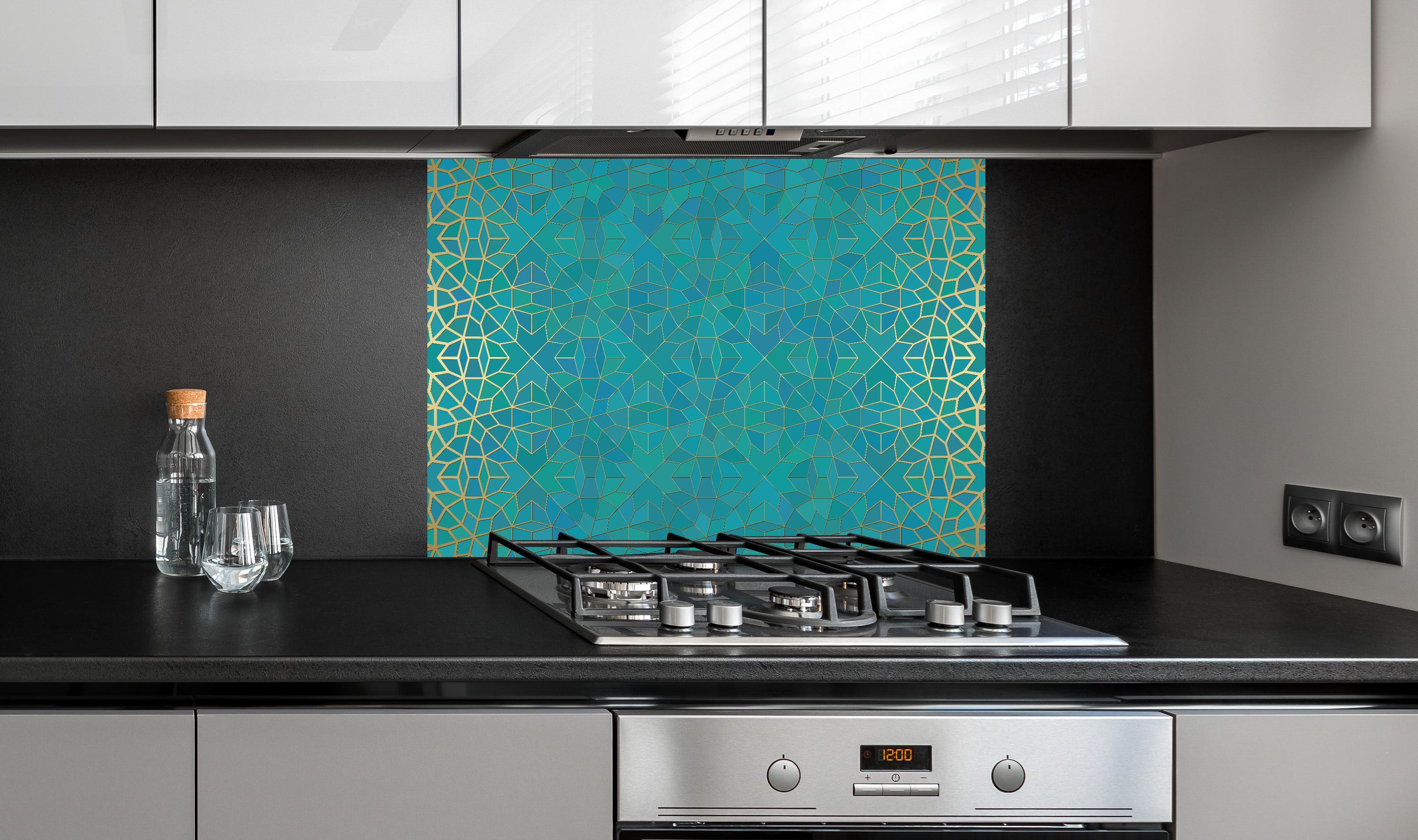 Spritzschutz - Geometrisches Muster mit Blauverlauf hinter einem Cerankochfeld zwischen Holz-Kochutensilien