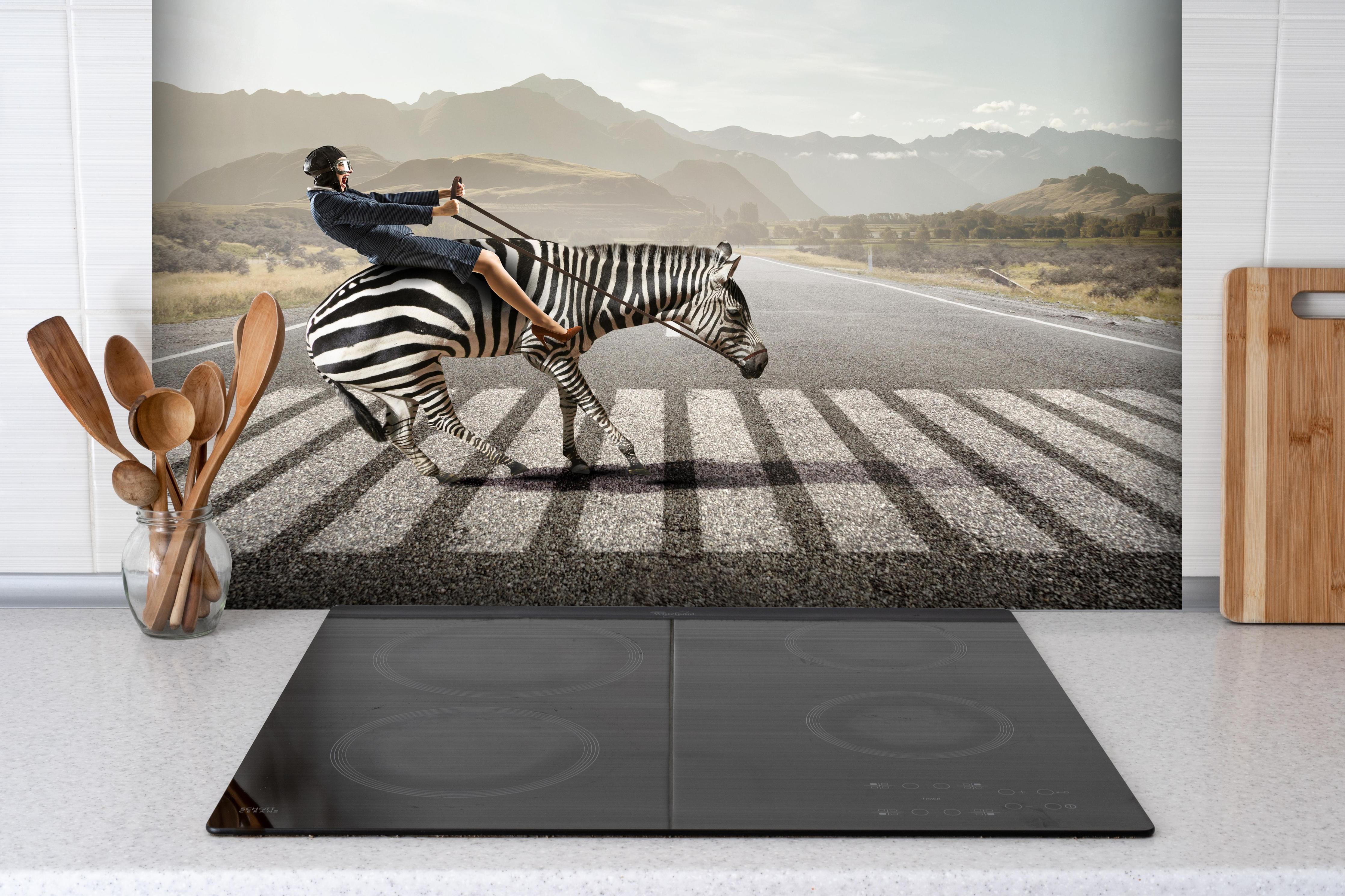Spritzschutz - Geschäftsfrau reitet Zebra in Landschaft hinter einem Cerankochfeld zwischen Holz-Kochutensilien