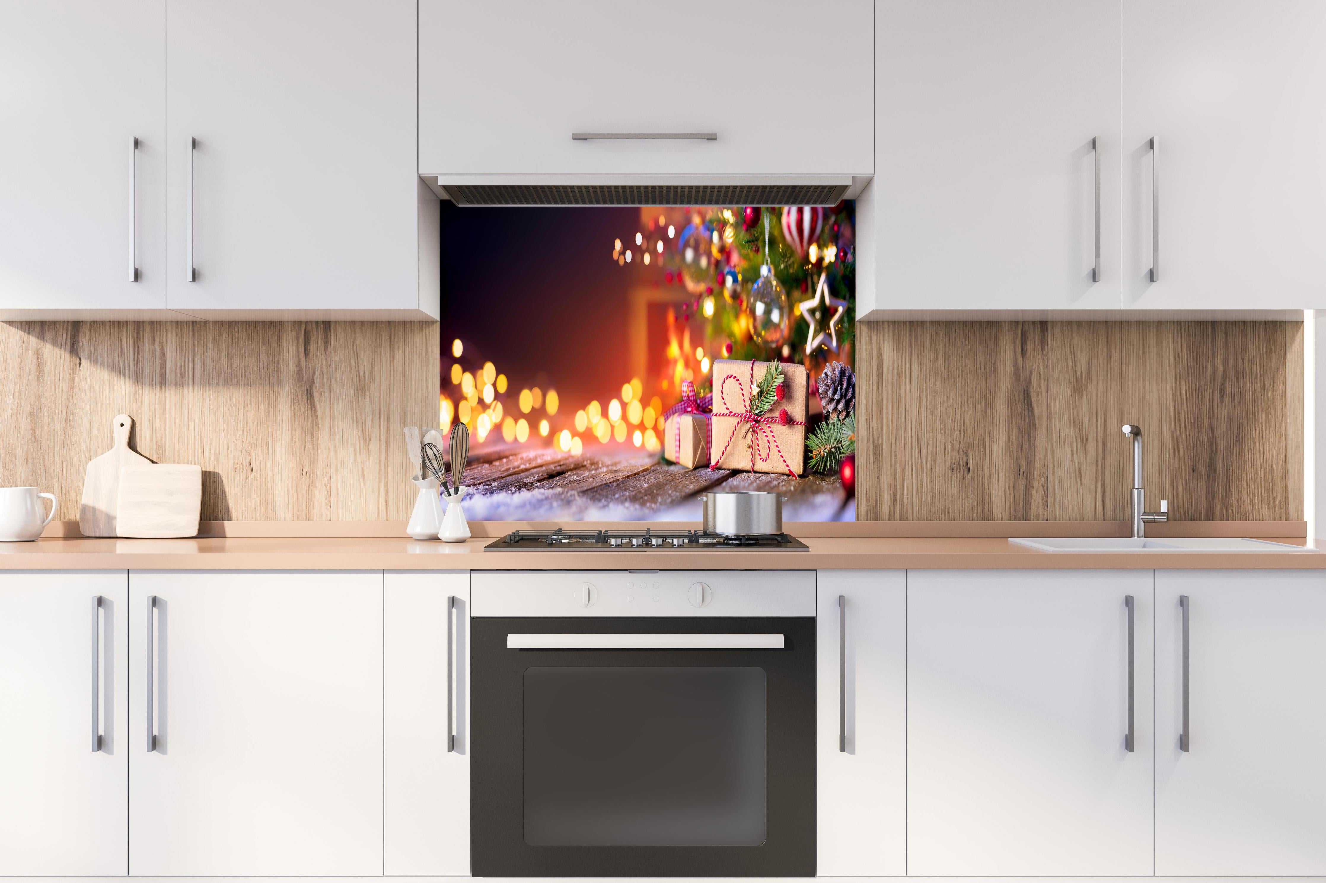 Spritzschutz - Geschenke unter dem Weihnachtsbaum hinter einem Cerankochfeld zwischen Holz-Kochutensilien