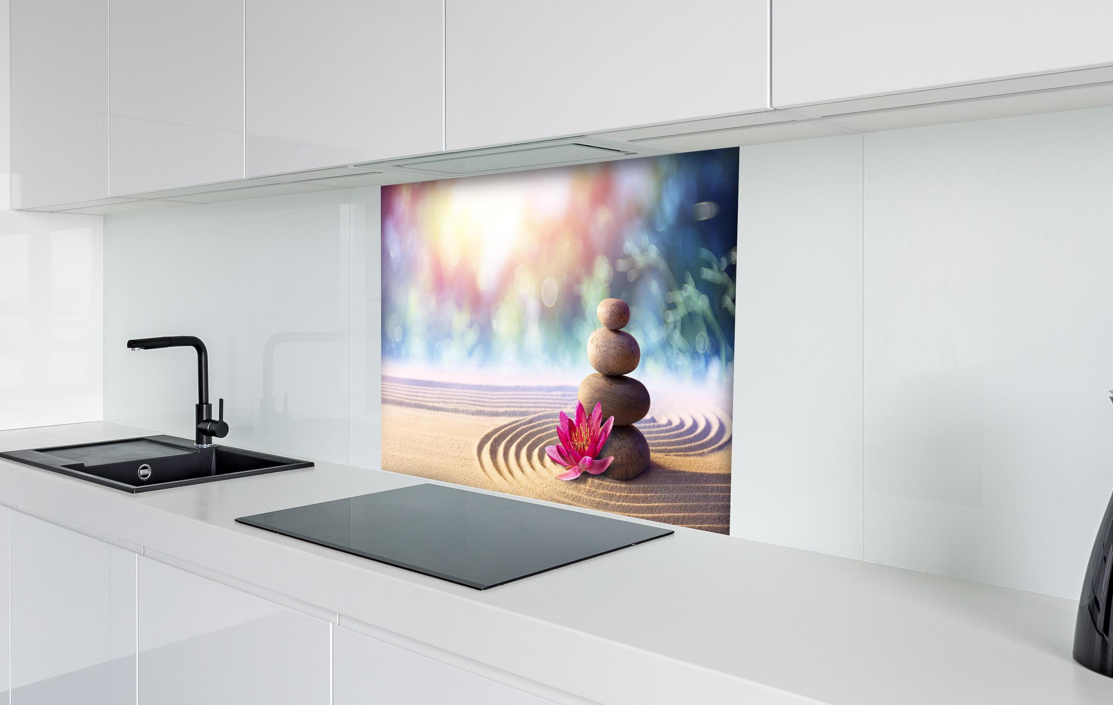 Spritzschutz - Gestapelte Meditation Steine hinter einem Cerankochfeld zwischen Holz-Kochutensilien