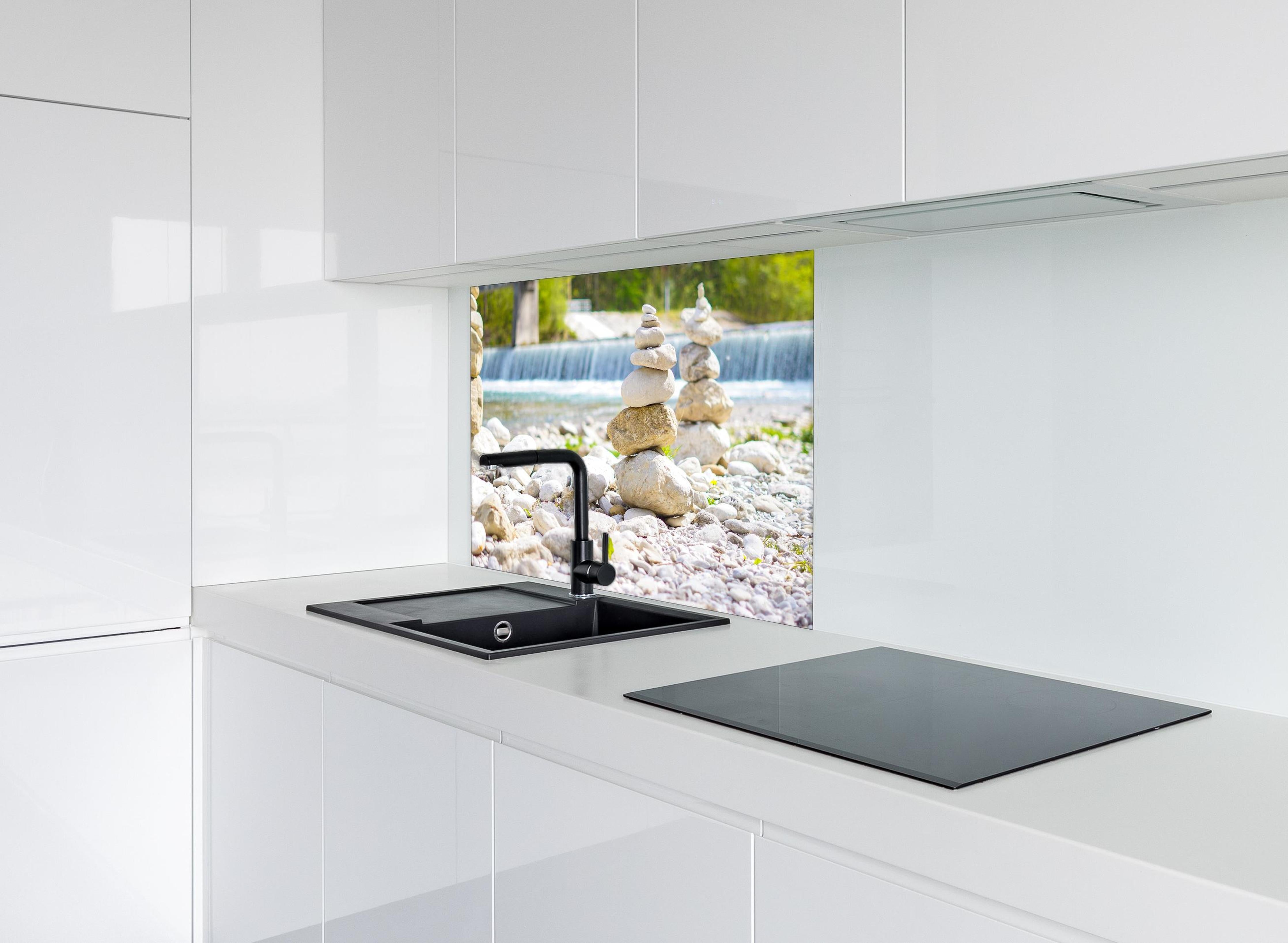 Spritzschutz - Gestapelte Steine am Fluss in Weiß-Grau hinter einem Cerankochfeld zwischen Holz-Kochutensilien