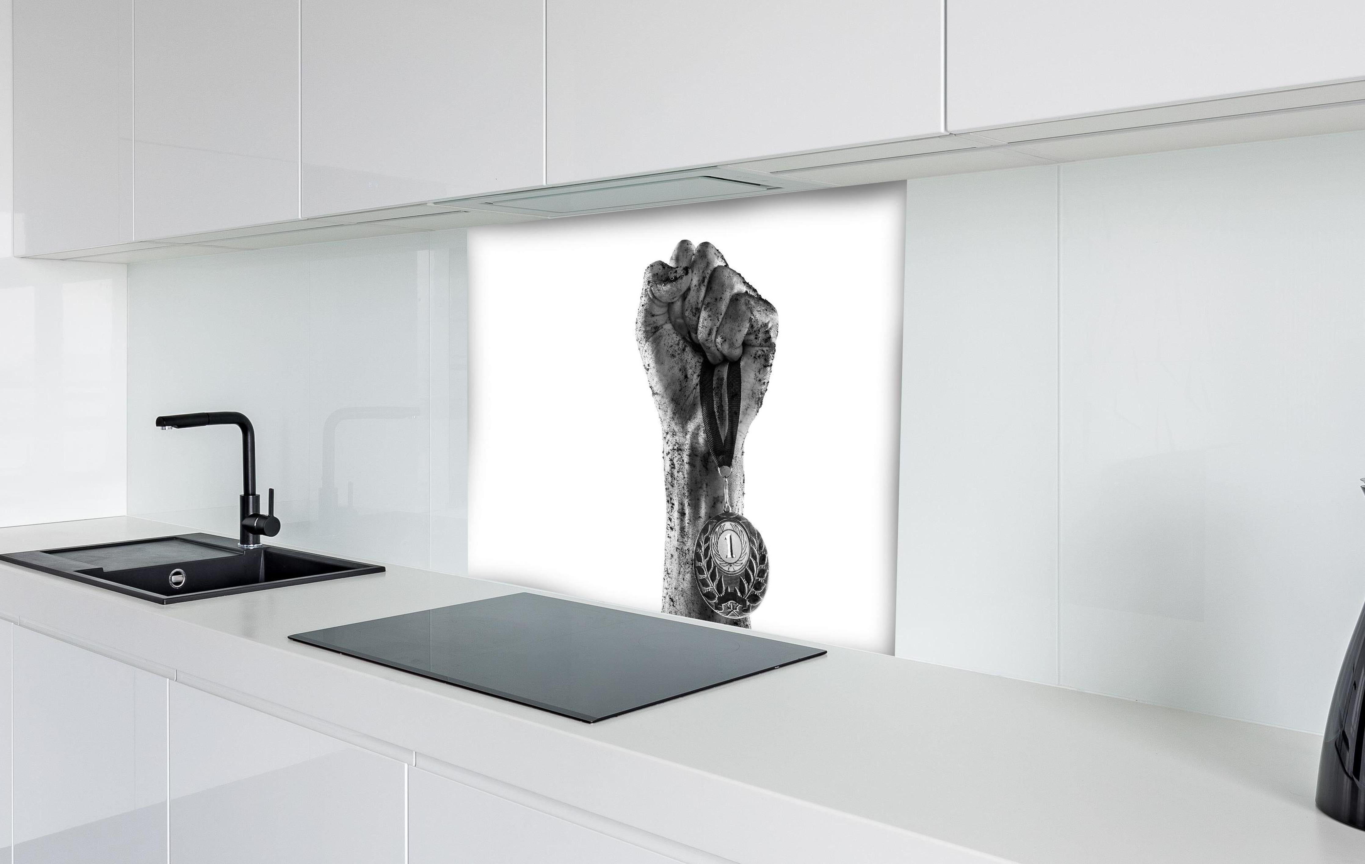 Spritzschutz - Gewinner mit einer Medaille hinter einem Cerankochfeld zwischen Holz-Kochutensilien