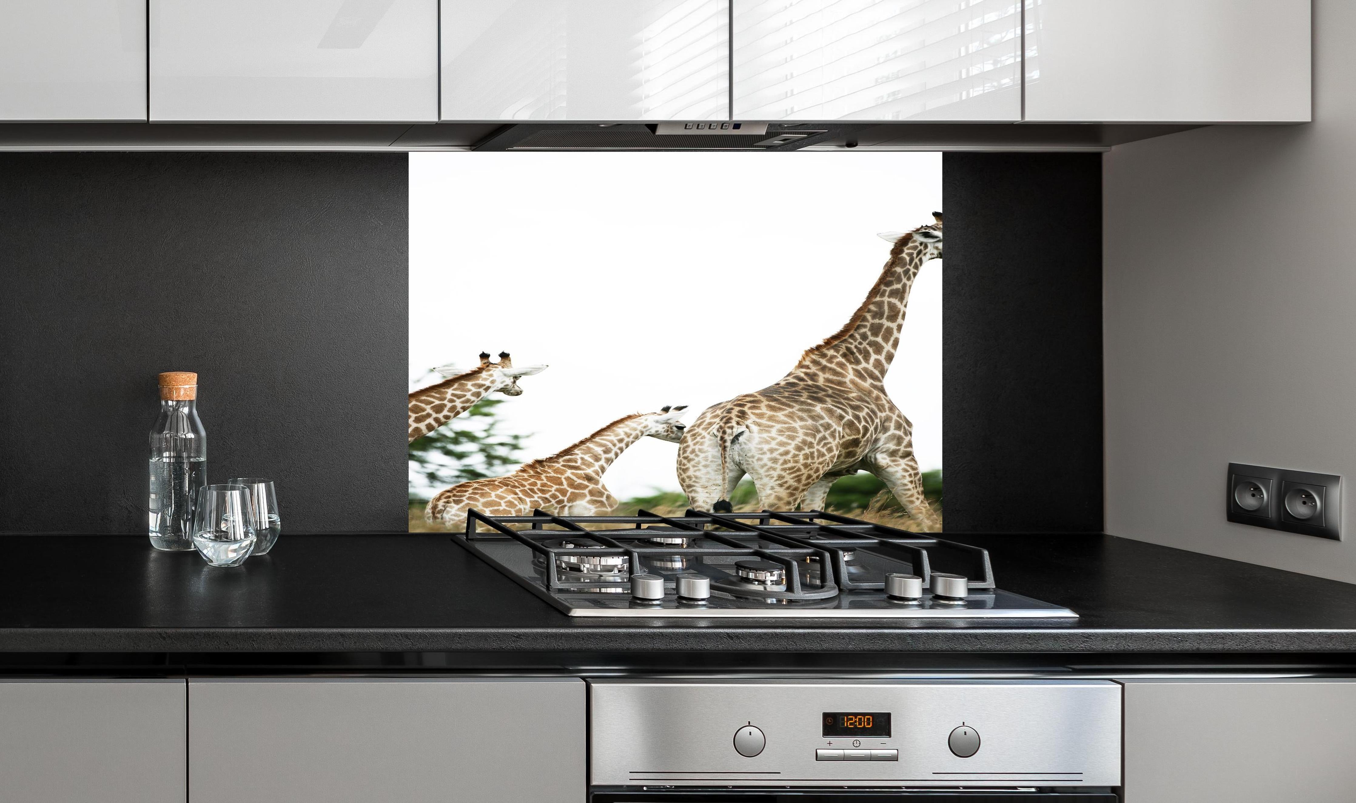 Spritzschutz - Giraffen Familie - hell hinter einem Cerankochfeld zwischen Holz-Kochutensilien