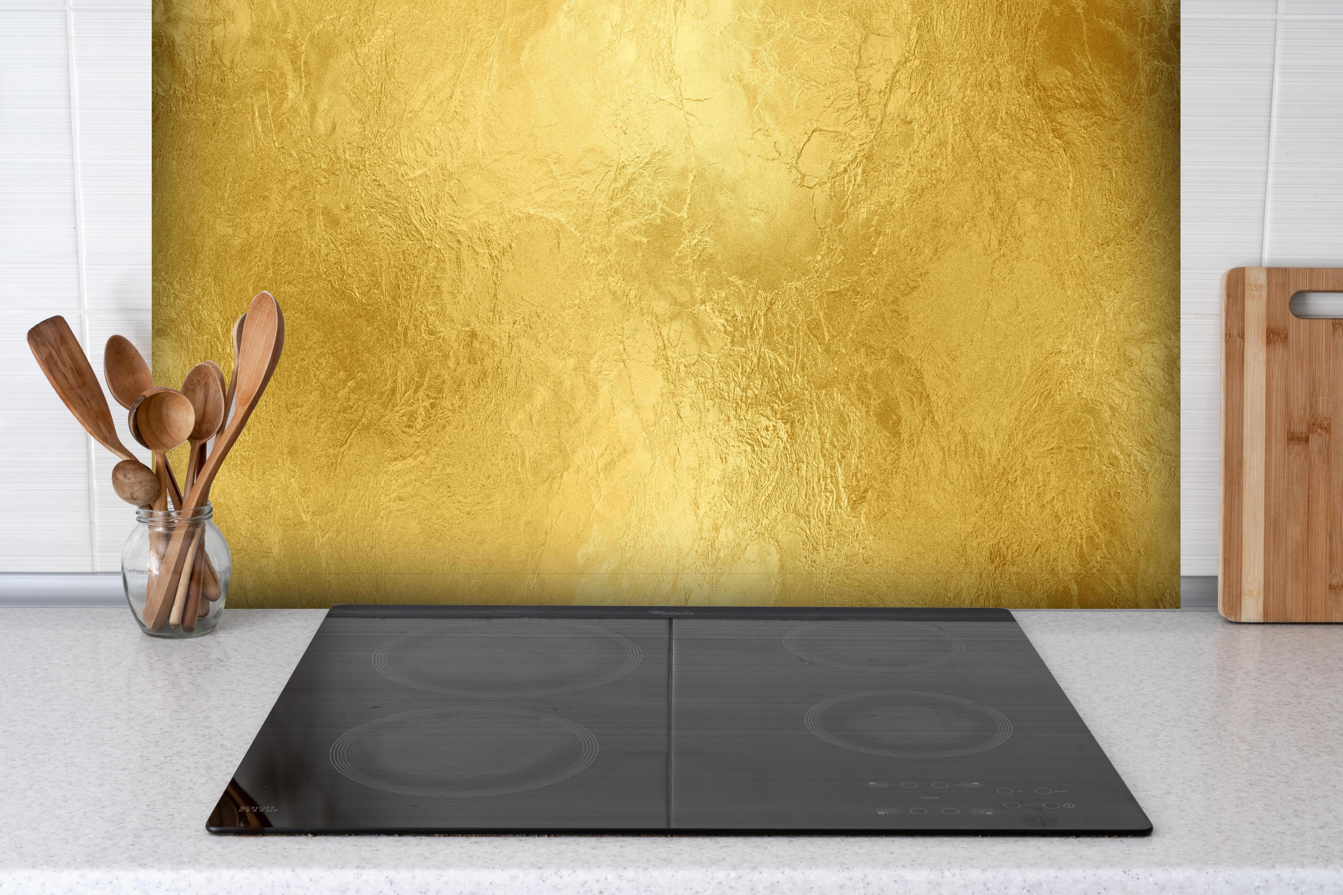 Spritzschutz - Glänzende Blattgold Textur hinter einem Cerankochfeld zwischen Holz-Kochutensilien