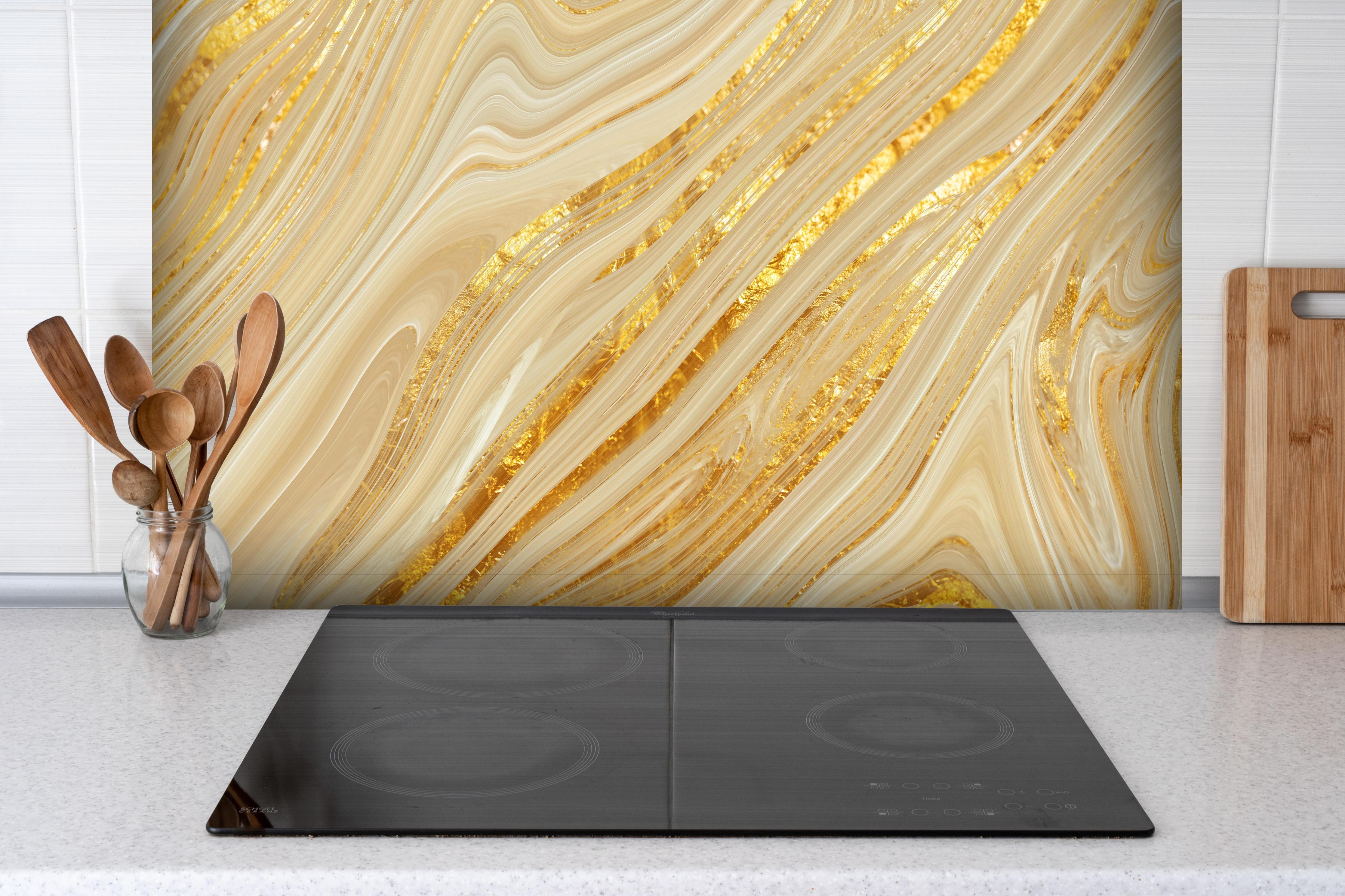 Spritzschutz - Goldene wellenförmige Marmorierung hinter einem Cerankochfeld zwischen Holz-Kochutensilien