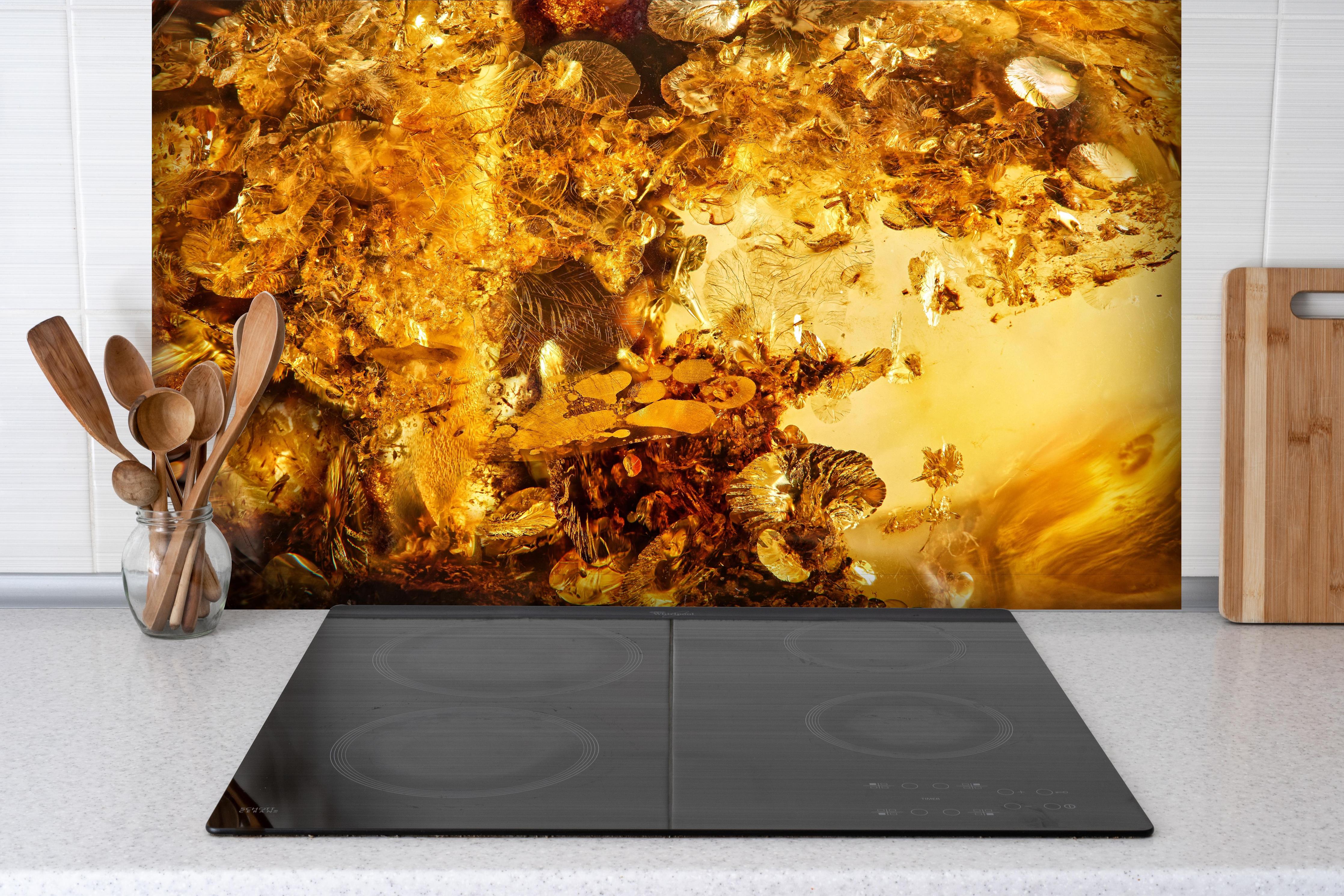 Spritzschutz - Goldener Kristall - Sonnenstein hinter einem Cerankochfeld zwischen Holz-Kochutensilien
