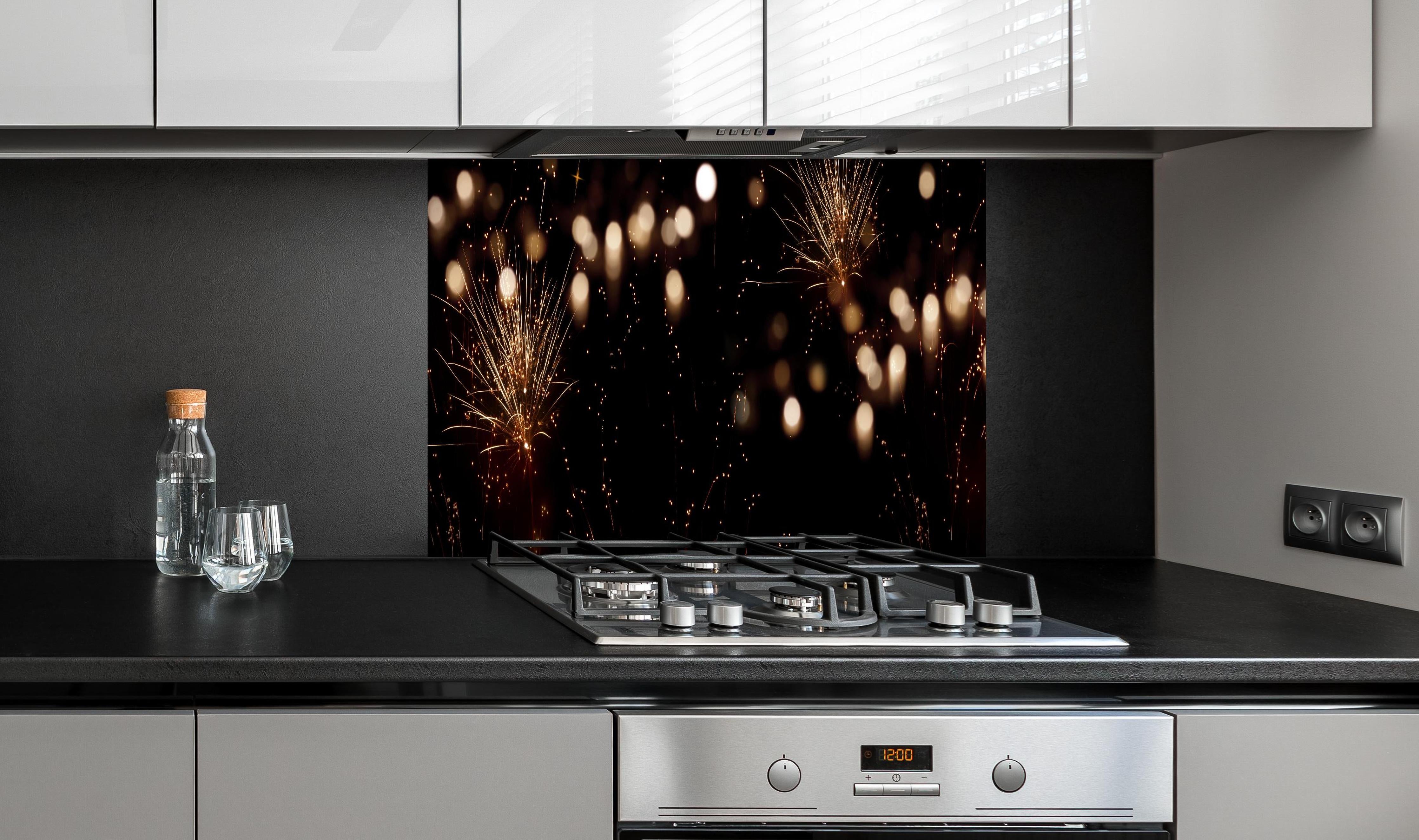 Spritzschutz - Goldenes Feuerwerk am Nachthimmel hinter einem Cerankochfeld zwischen Holz-Kochutensilien