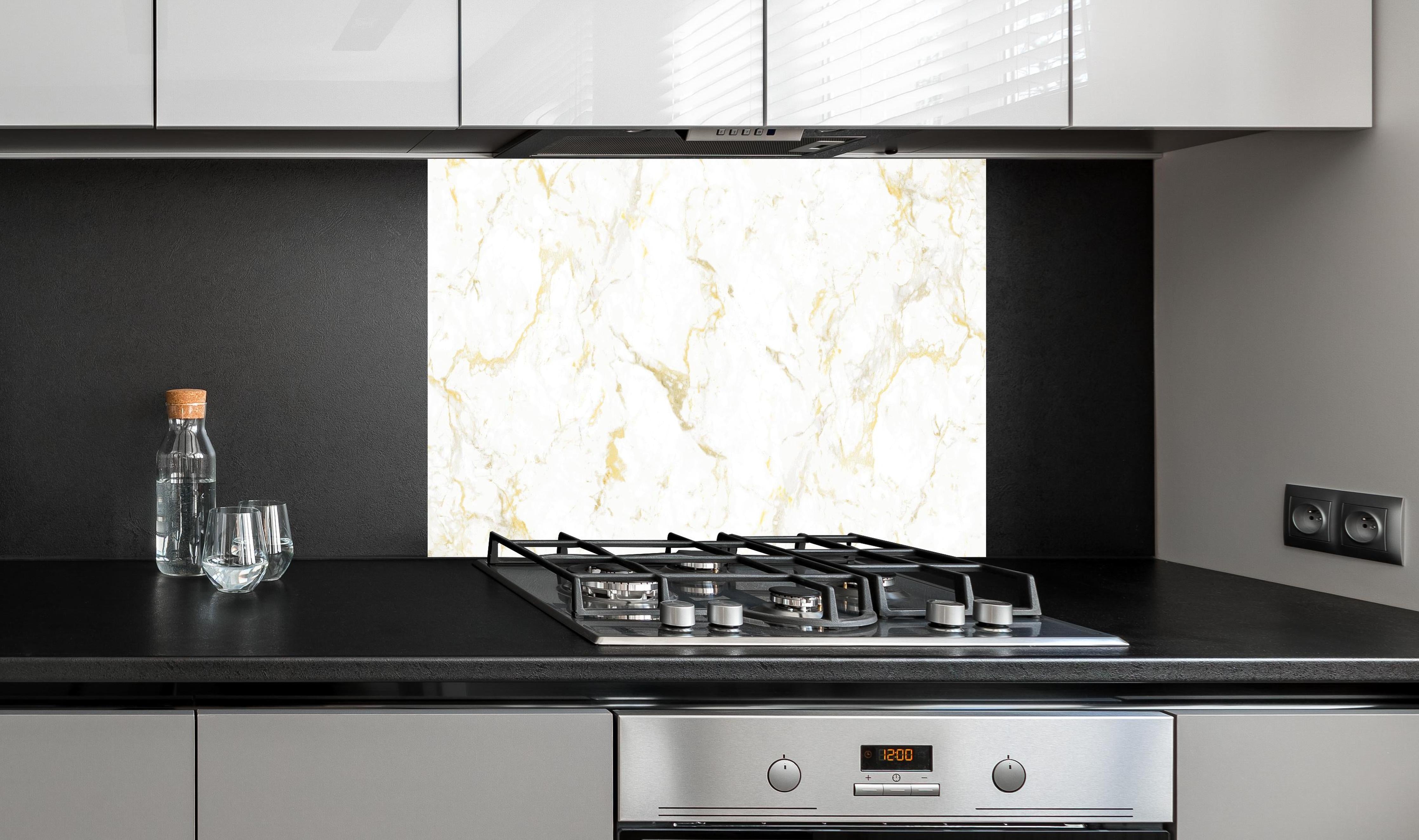 Spritzschutz - Goldmarmor Textur hinter einem Cerankochfeld zwischen Holz-Kochutensilien