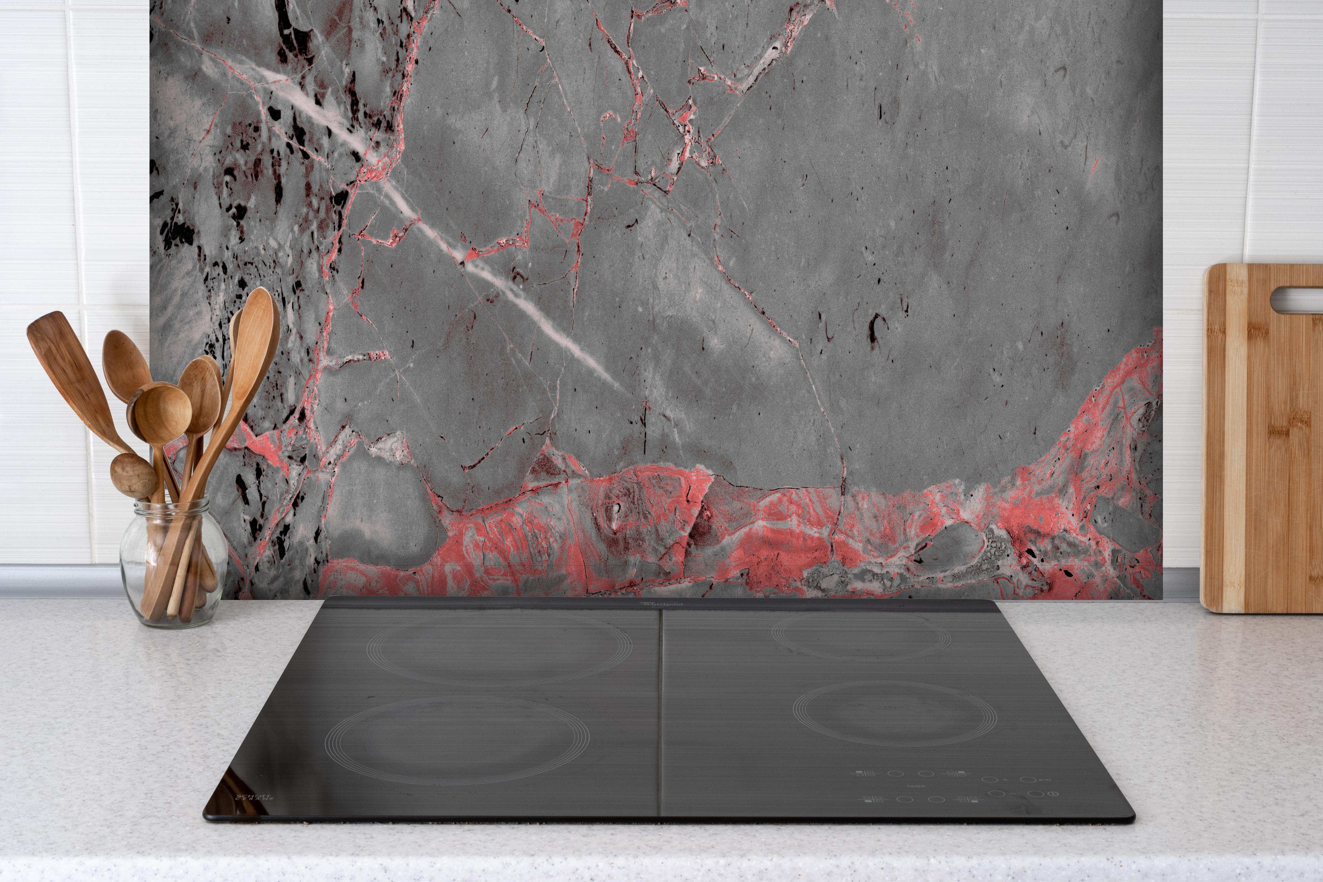 Spritzschutz - Gräulich-rote Marmor Textur hinter einem Cerankochfeld zwischen Holz-Kochutensilien