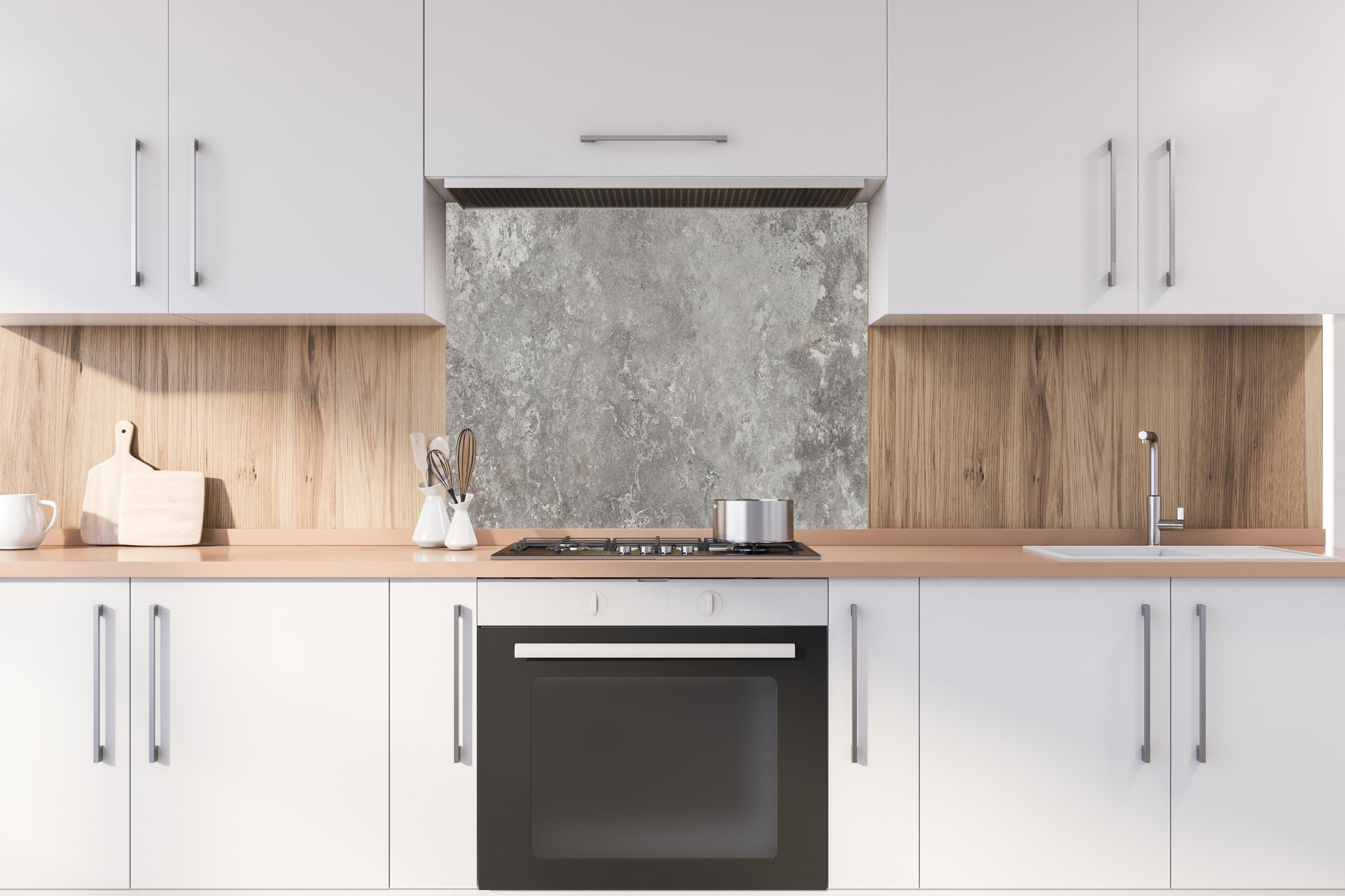 Spritzschutz - Gräulicher Zement hinter einem Cerankochfeld zwischen Holz-Kochutensilien