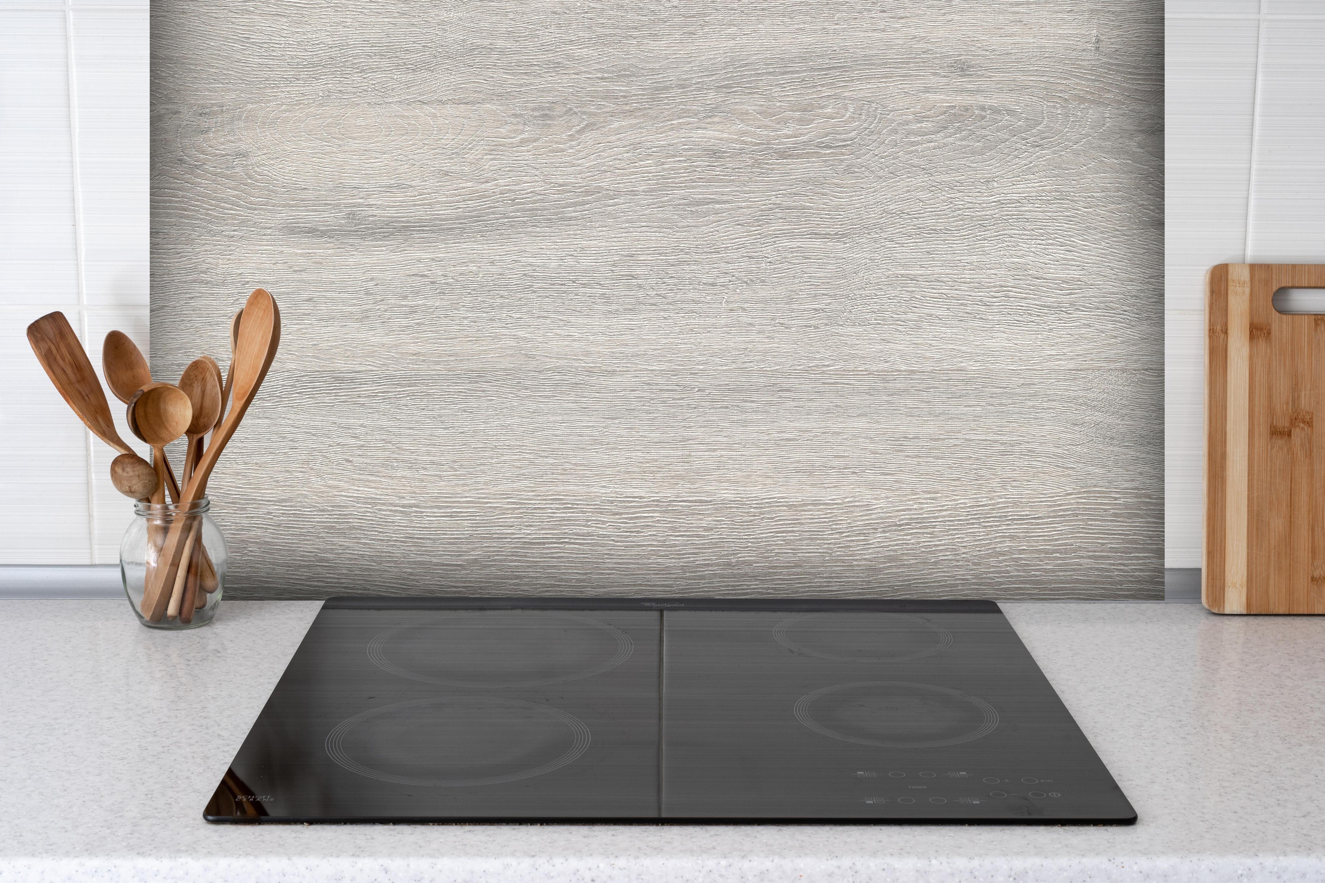 Spritzschutz - Gräuliches Eichenholzplatte hinter einem Cerankochfeld zwischen Holz-Kochutensilien