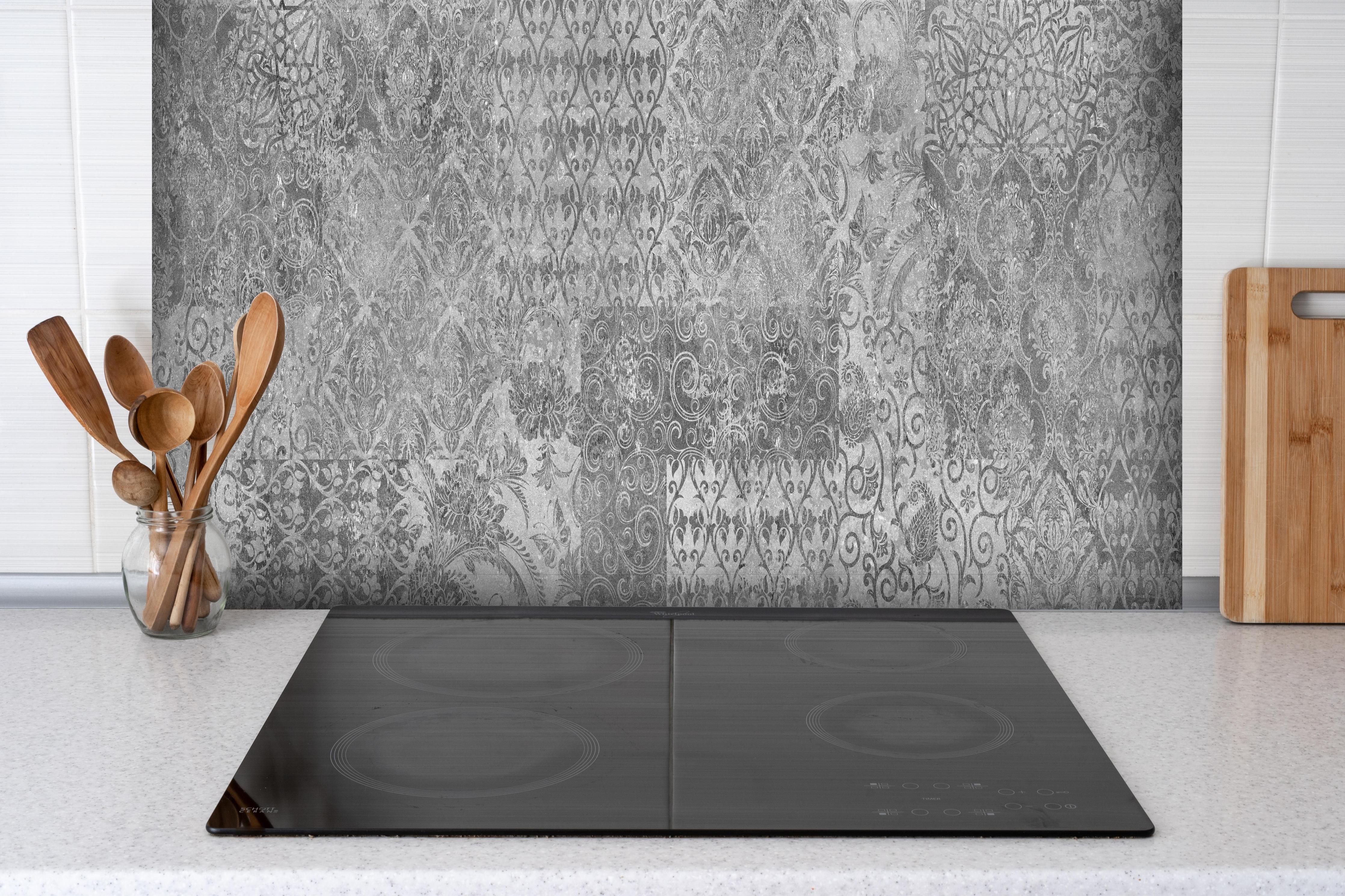 Spritzschutz - Gräuliches Mosaik Muster hinter einem Cerankochfeld zwischen Holz-Kochutensilien