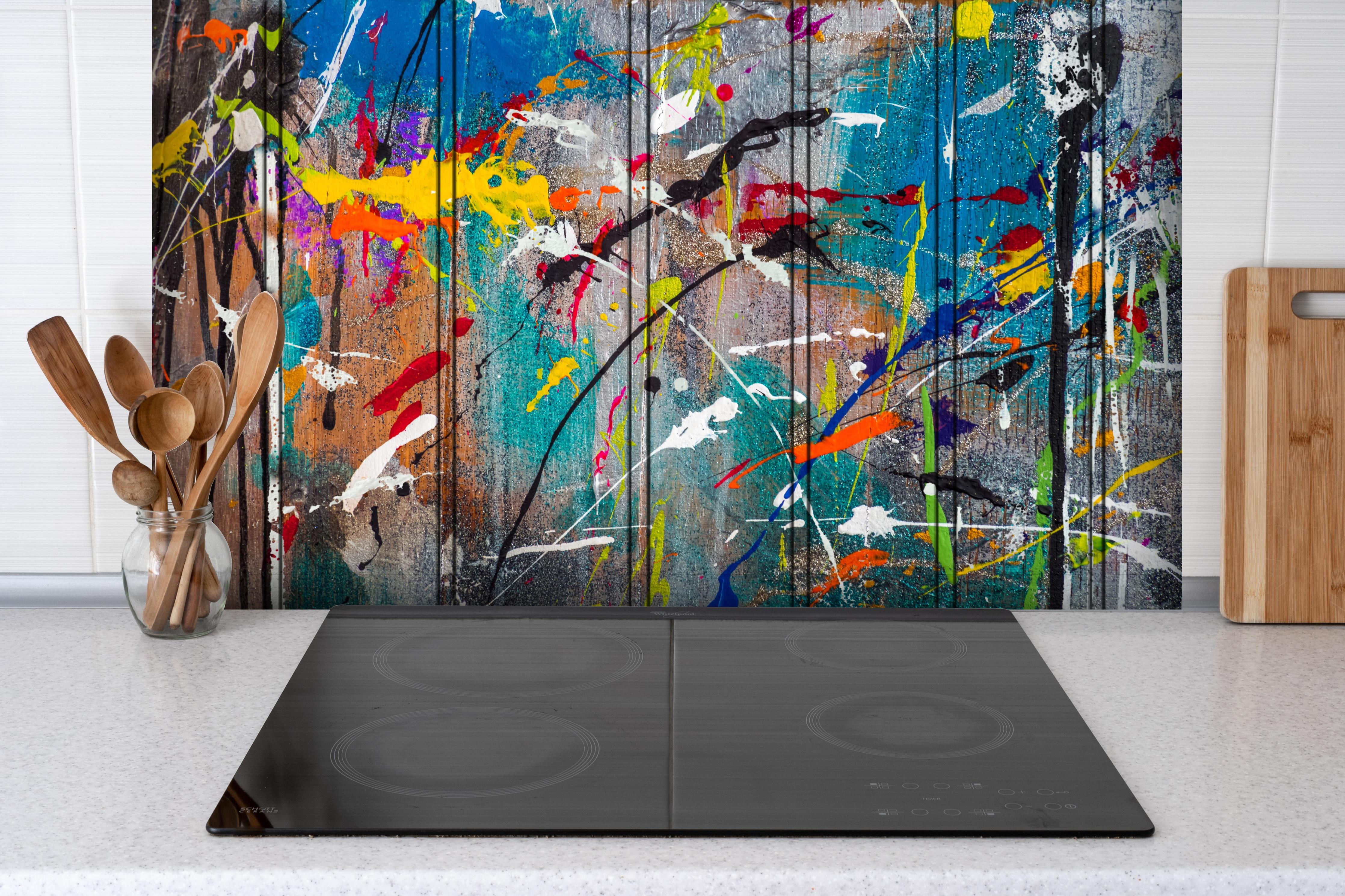 Spritzschutz - Graffiti auf Holz hinter einem Cerankochfeld zwischen Holz-Kochutensilien