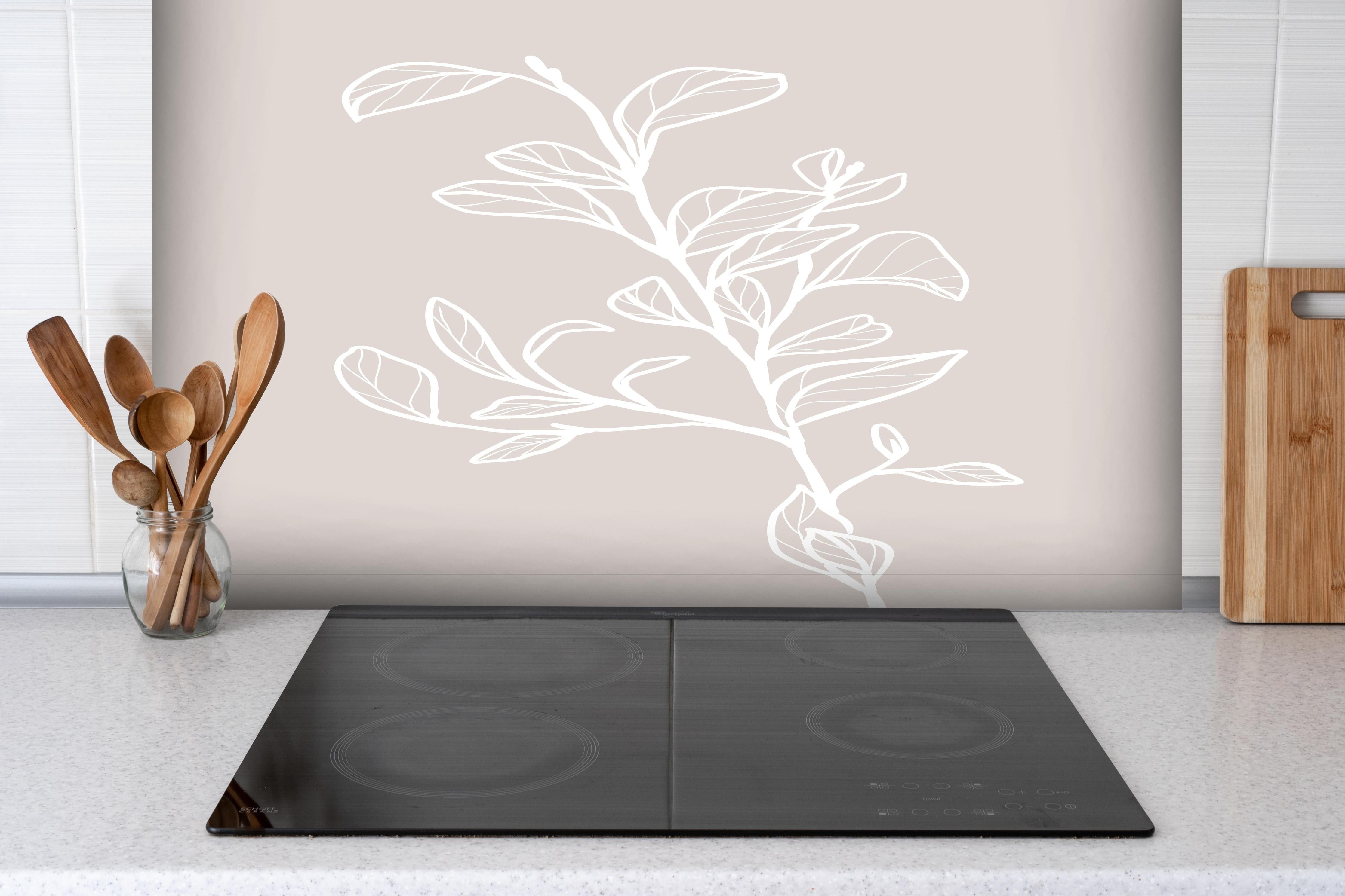 Spritzschutz - Grafische Blattzweigdarstellung in Beige hinter einem Cerankochfeld zwischen Holz-Kochutensilien