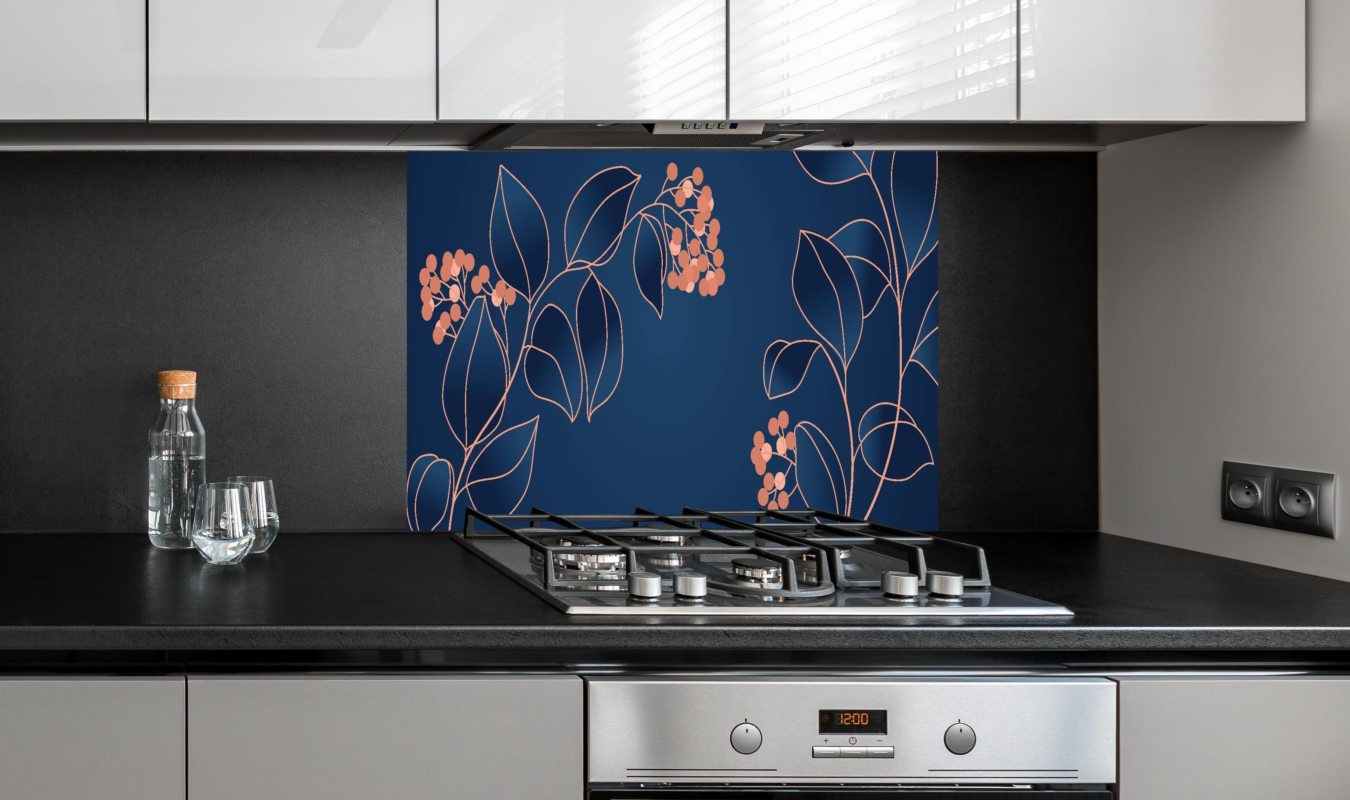 Spritzschutz - Grafische Blütenmotive in Blau und Orange hinter einem Cerankochfeld zwischen Holz-Kochutensilien