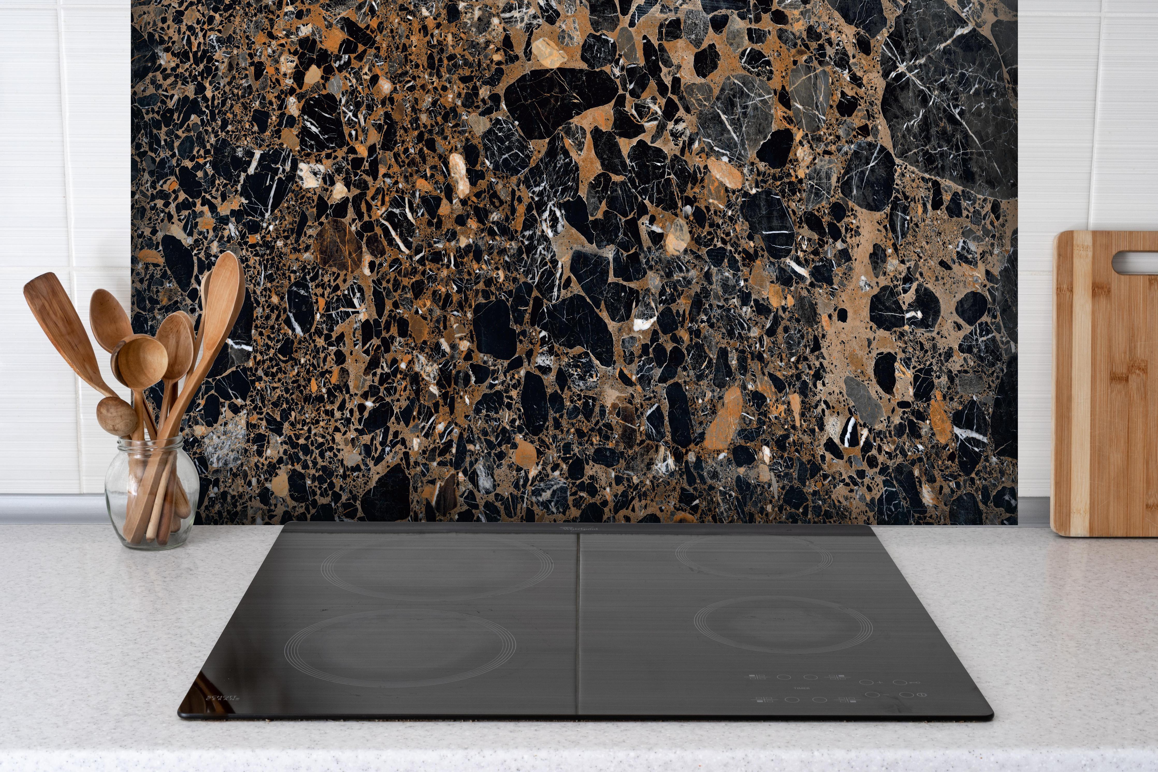 Spritzschutz - Granit luxus Textur hinter einem Cerankochfeld zwischen Holz-Kochutensilien