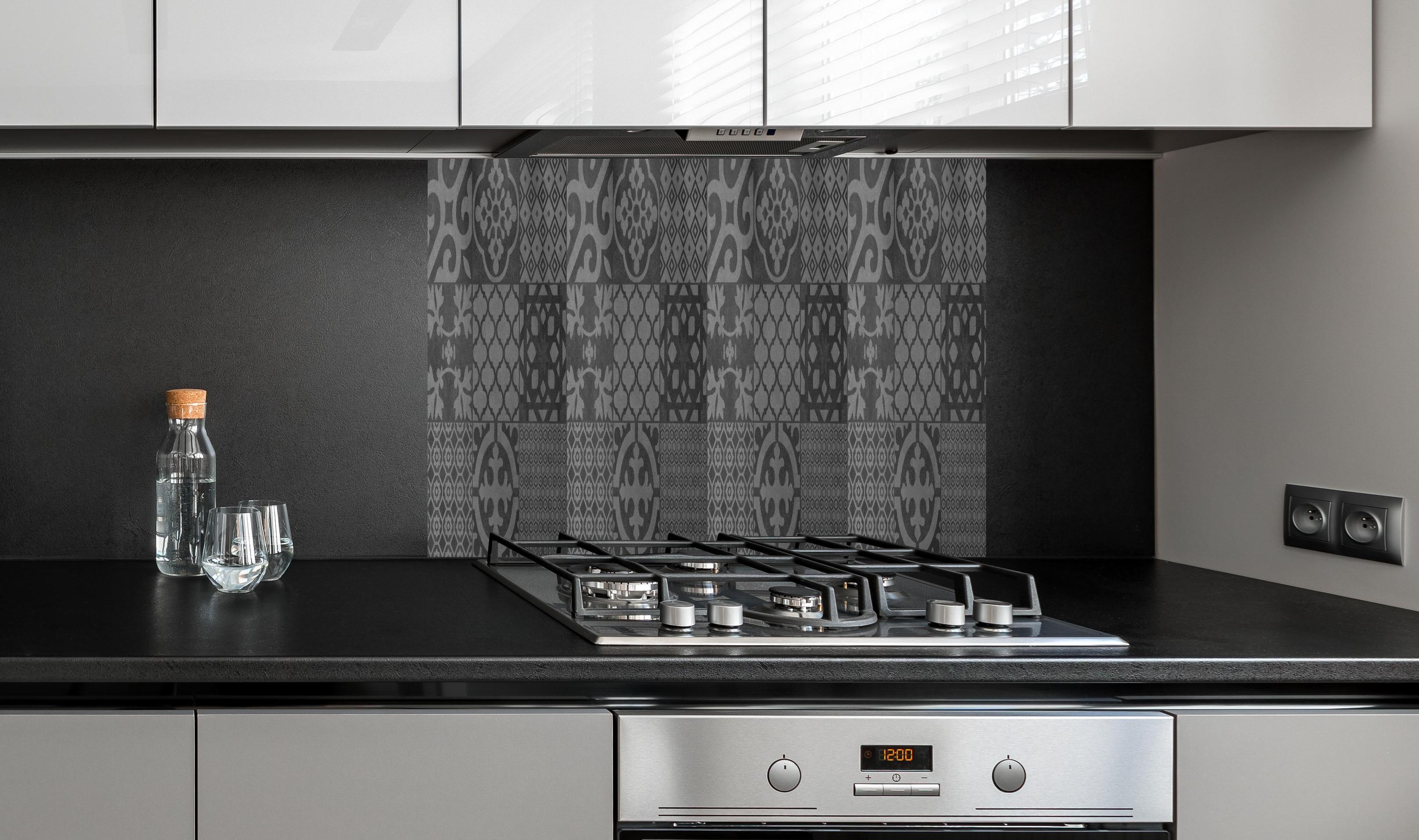 Spritzschutz - Grau vintage Fliesen hinter einem Cerankochfeld zwischen Holz-Kochutensilien