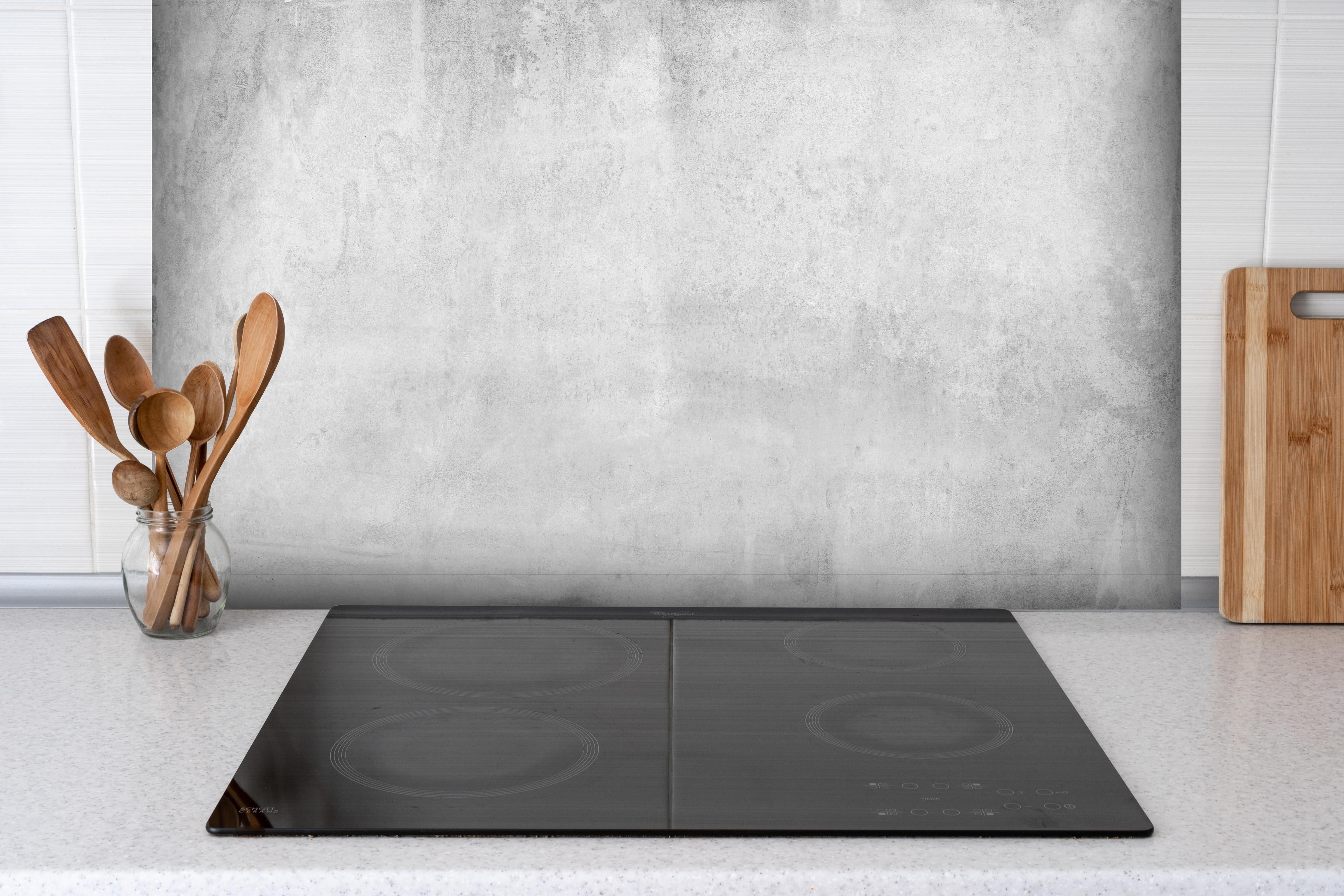 Spritzschutz - Graue Grunge Betonwand hinter einem Cerankochfeld zwischen Holz-Kochutensilien