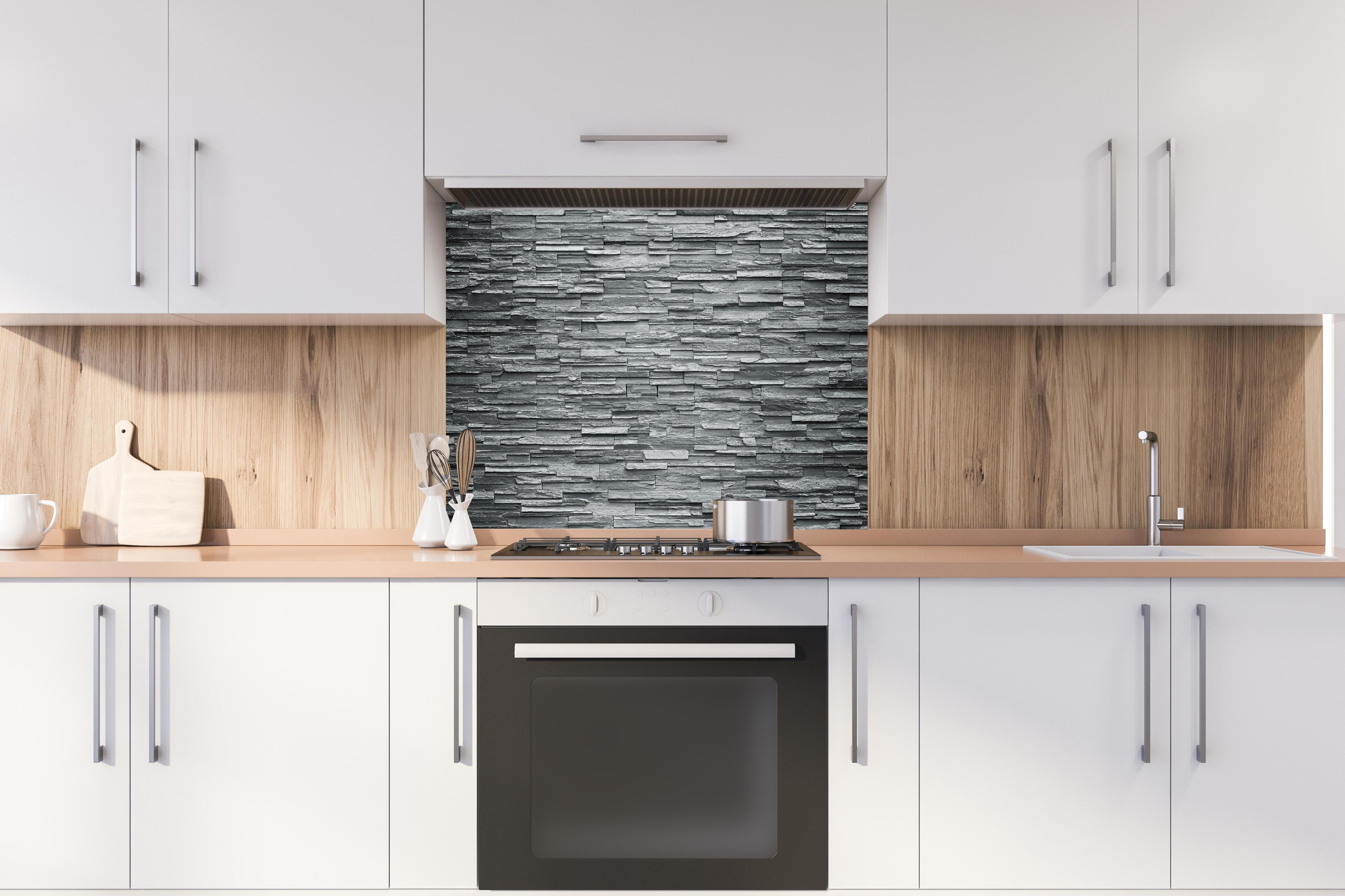 Spritzschutz - Graue Steinziegel hinter einem Cerankochfeld zwischen Holz-Kochutensilien