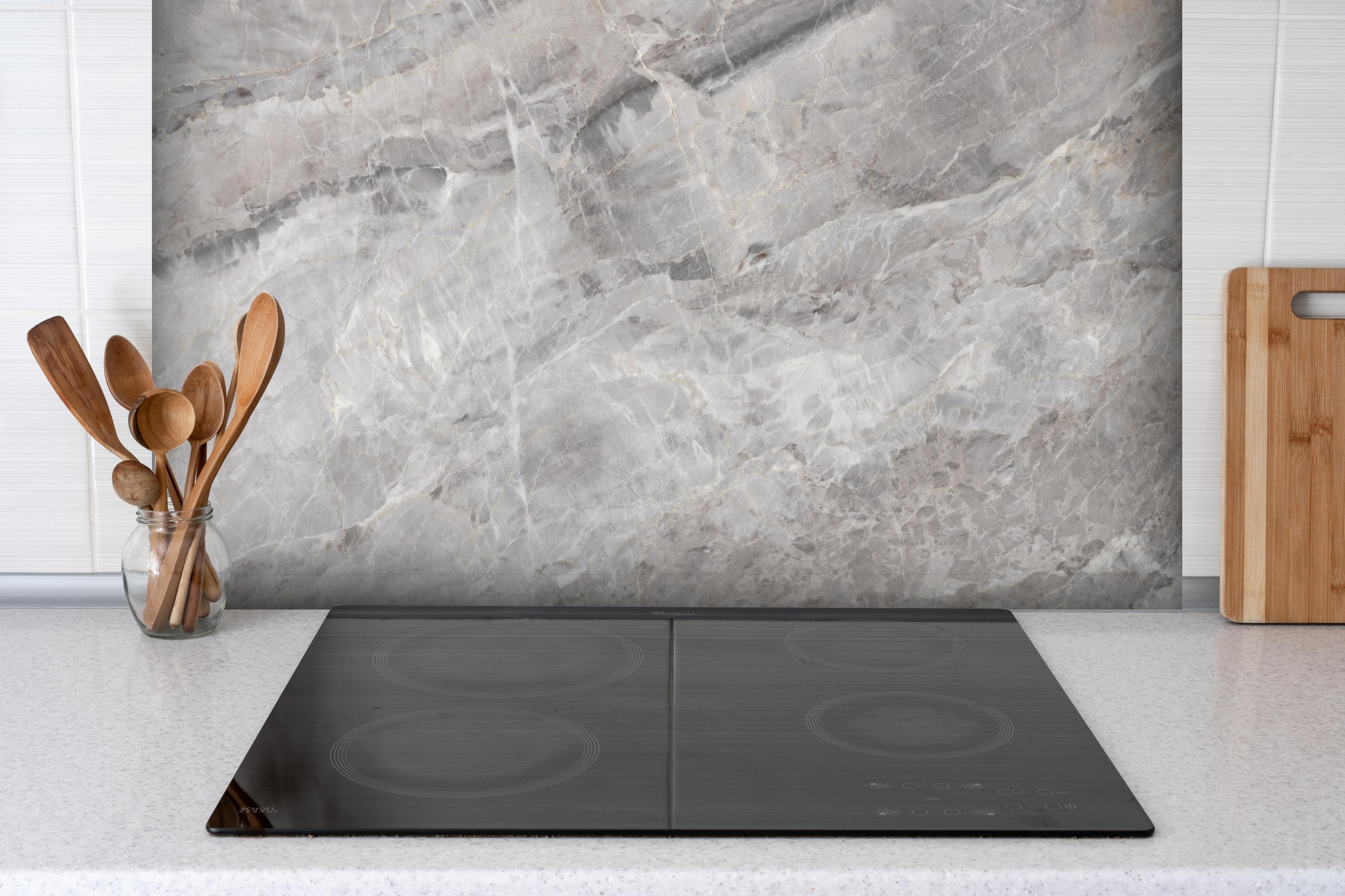 Spritzschutz - Grauer Marmor - Granit hinter einem Cerankochfeld zwischen Holz-Kochutensilien