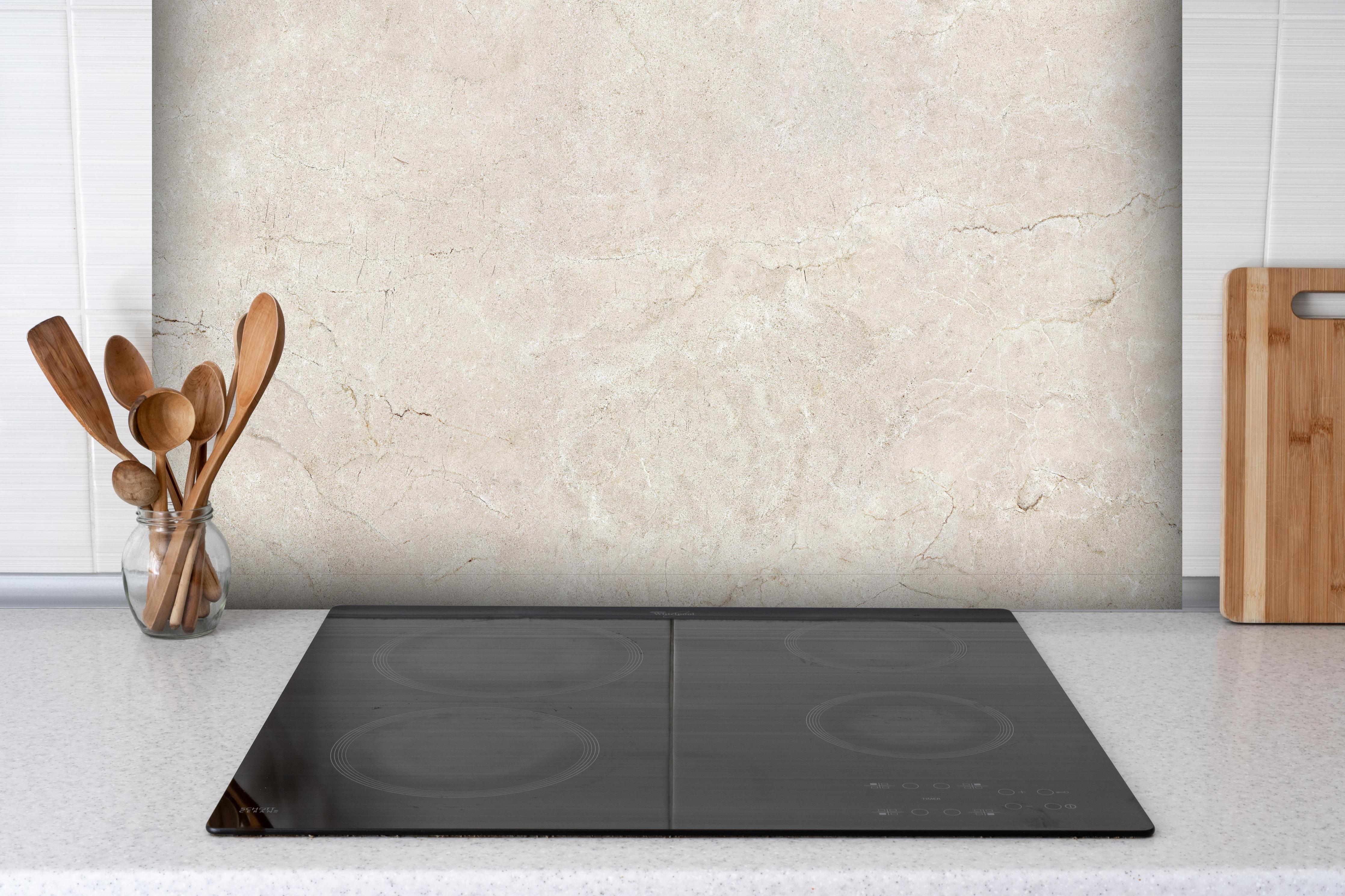 Spritzschutz - Grauer Marmor auf steinigem Hintergrund hinter einem Cerankochfeld zwischen Holz-Kochutensilien