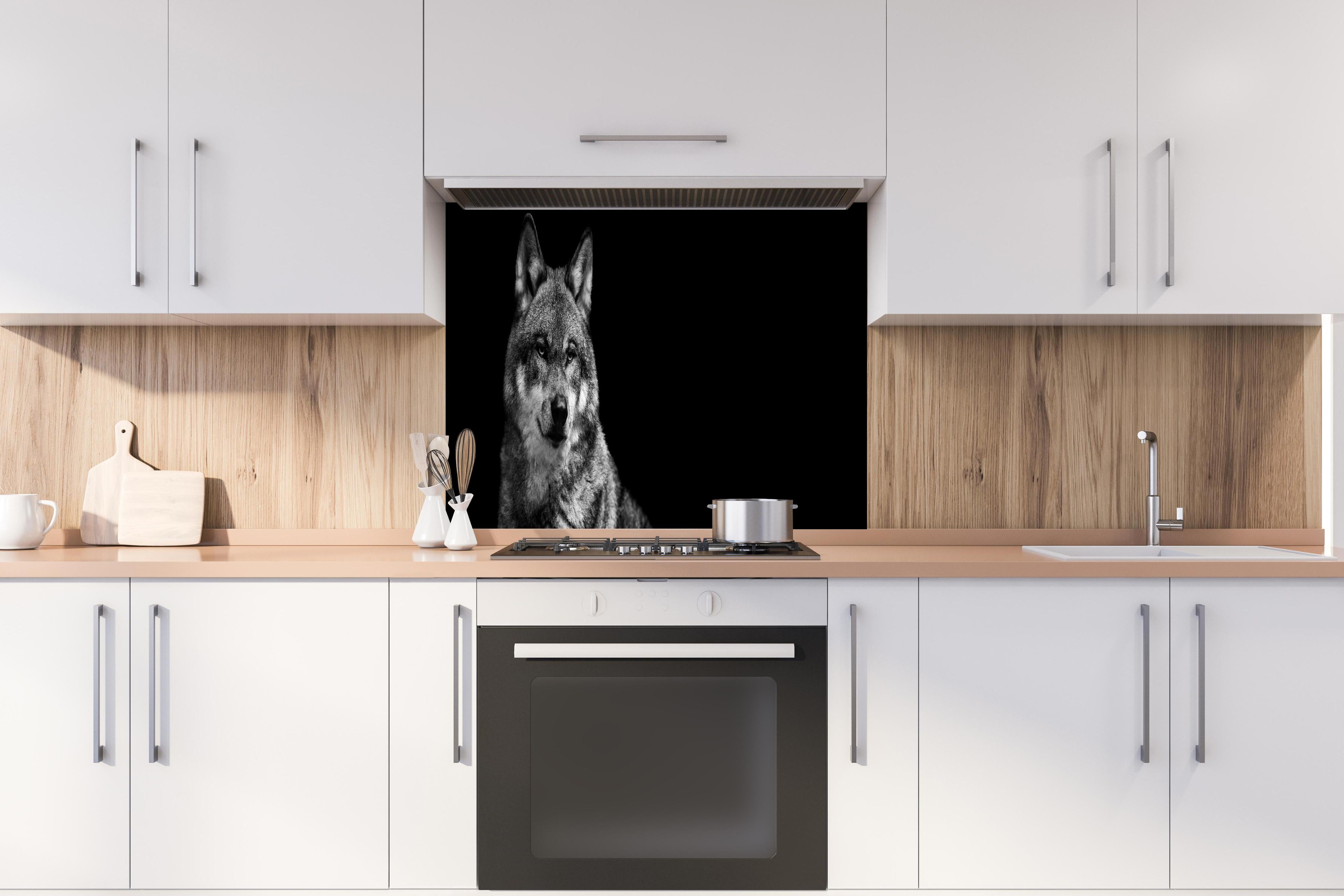 Spritzschutz - Grauer Wolf auf schwarzem Hintergrund hinter einem Cerankochfeld zwischen Holz-Kochutensilien