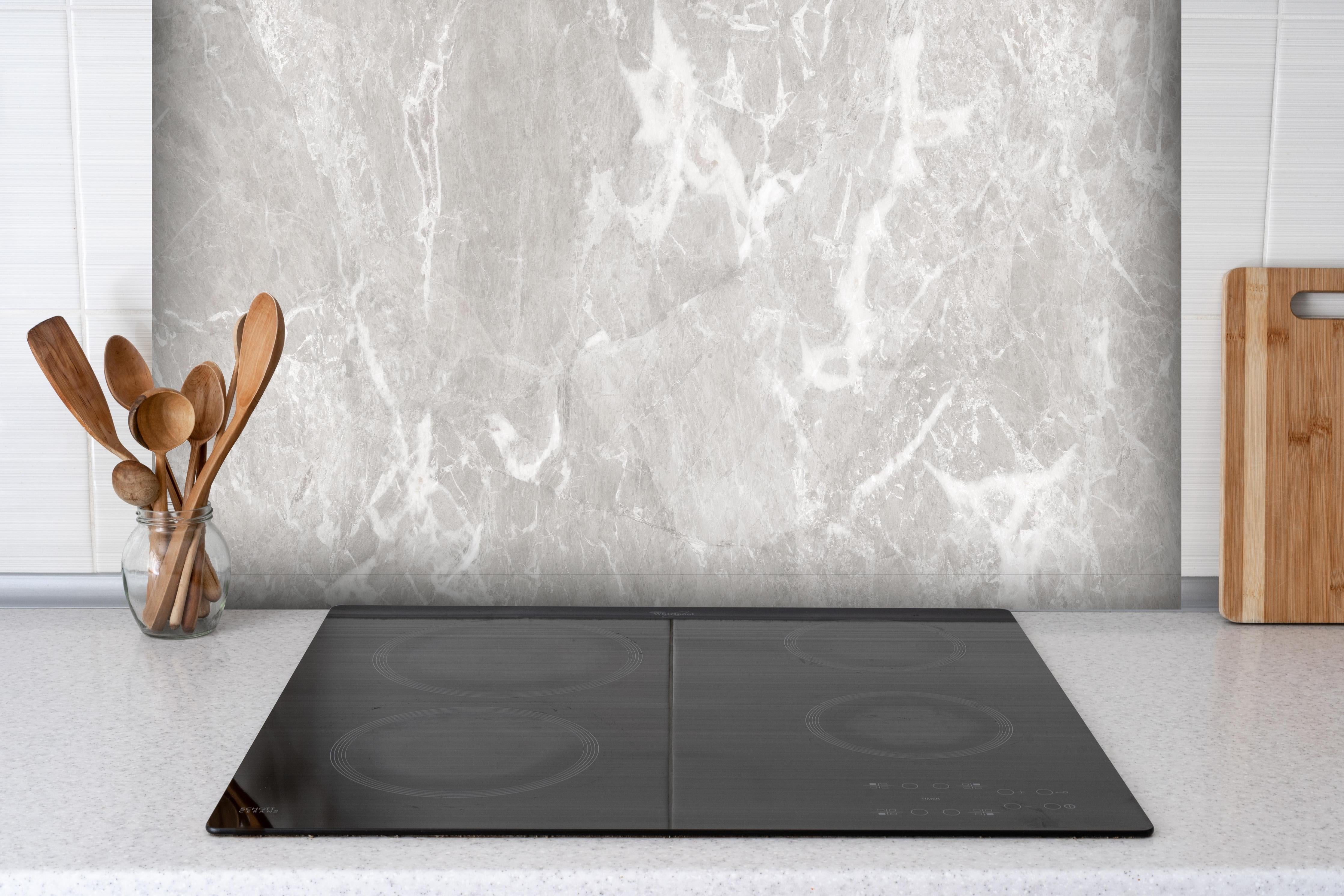Spritzschutz - Graues Fliesen Muster hinter einem Cerankochfeld zwischen Holz-Kochutensilien