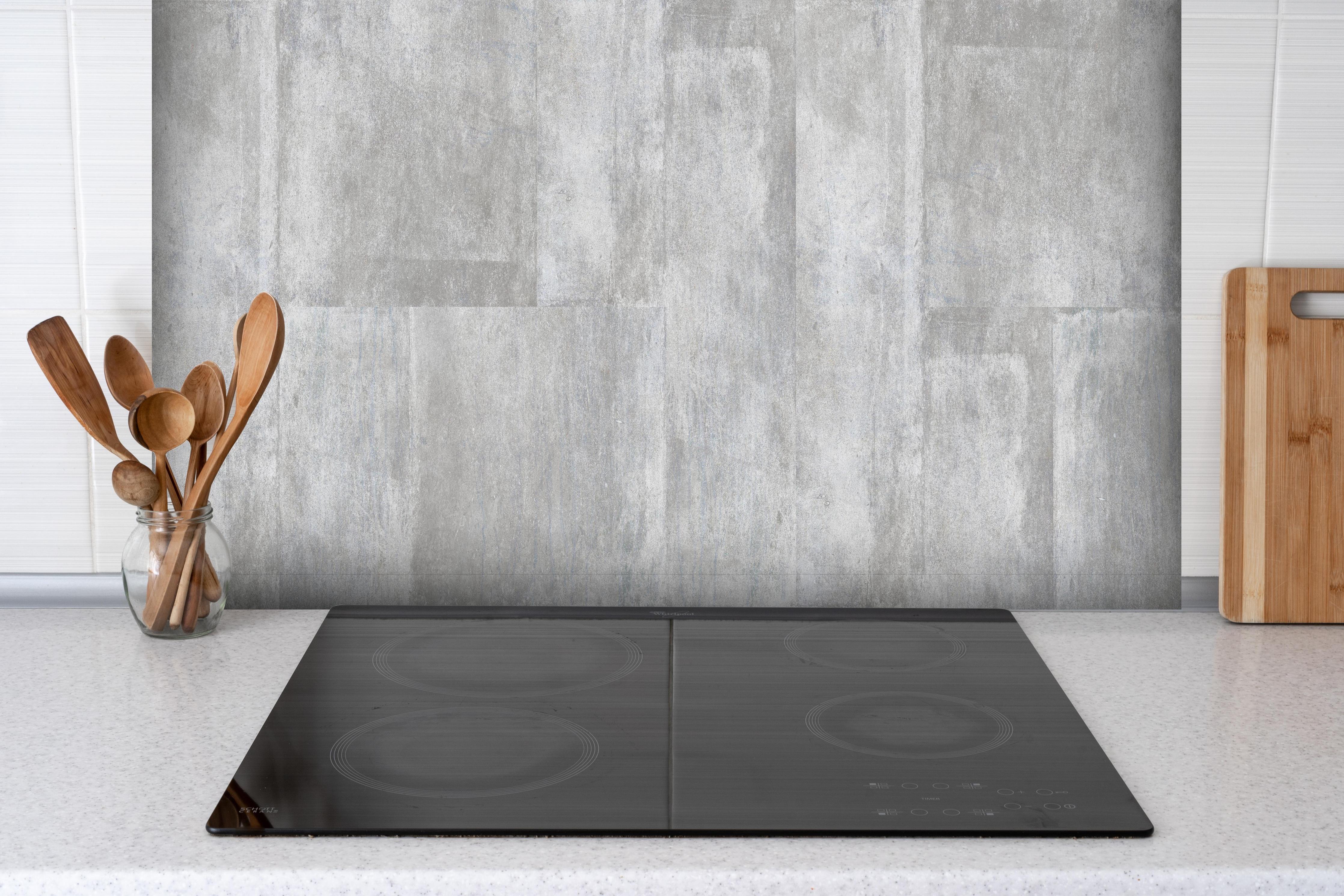 Spritzschutz - Grauweiße Betonblockwand Strukturiert hinter einem Cerankochfeld zwischen Holz-Kochutensilien
