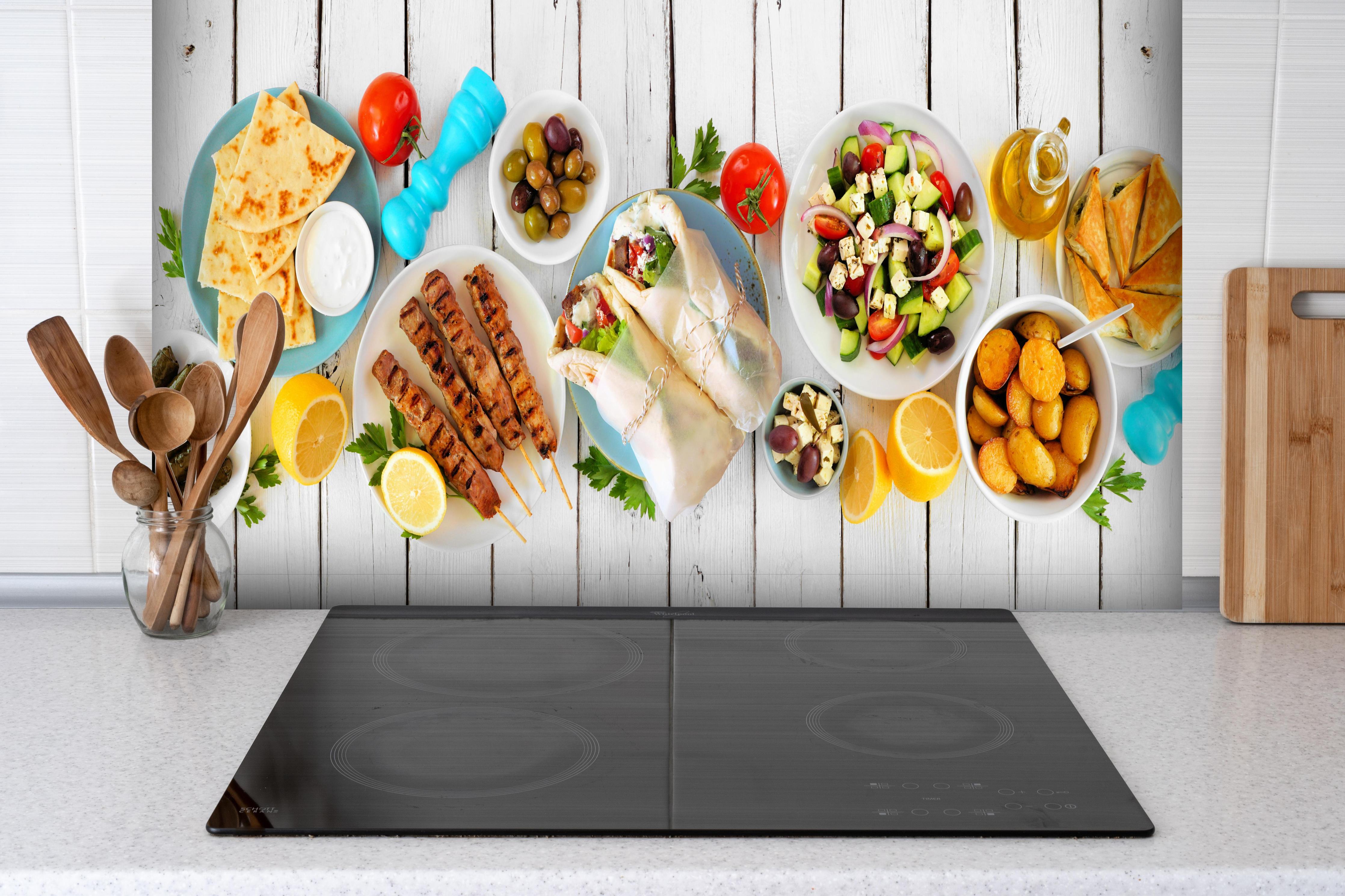 Spritzschutz - Griechisches Essen hinter einem Cerankochfeld zwischen Holz-Kochutensilien