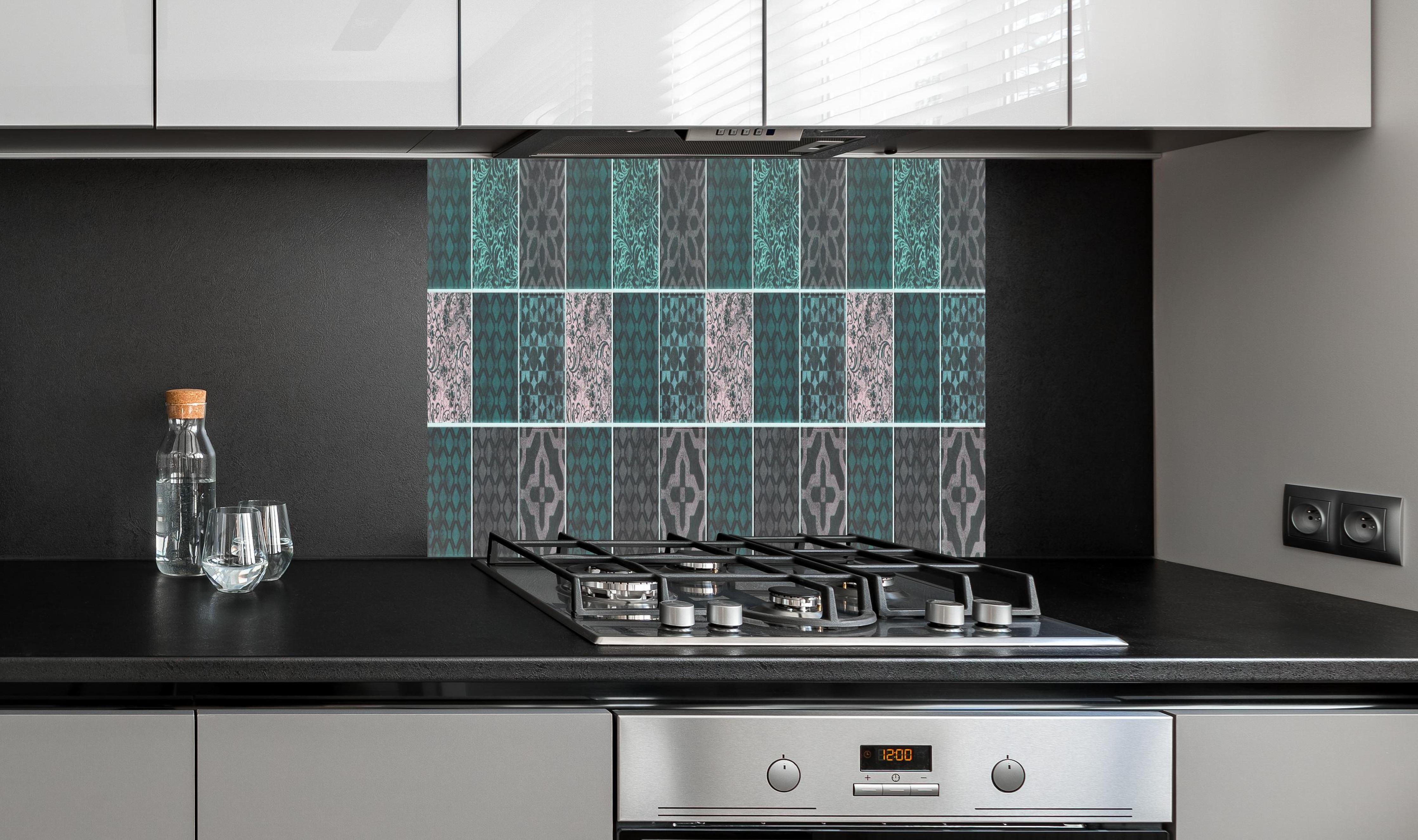 Spritzschutz - Grün rosafarbige Vintage Fliesen hinter einem Cerankochfeld zwischen Holz-Kochutensilien