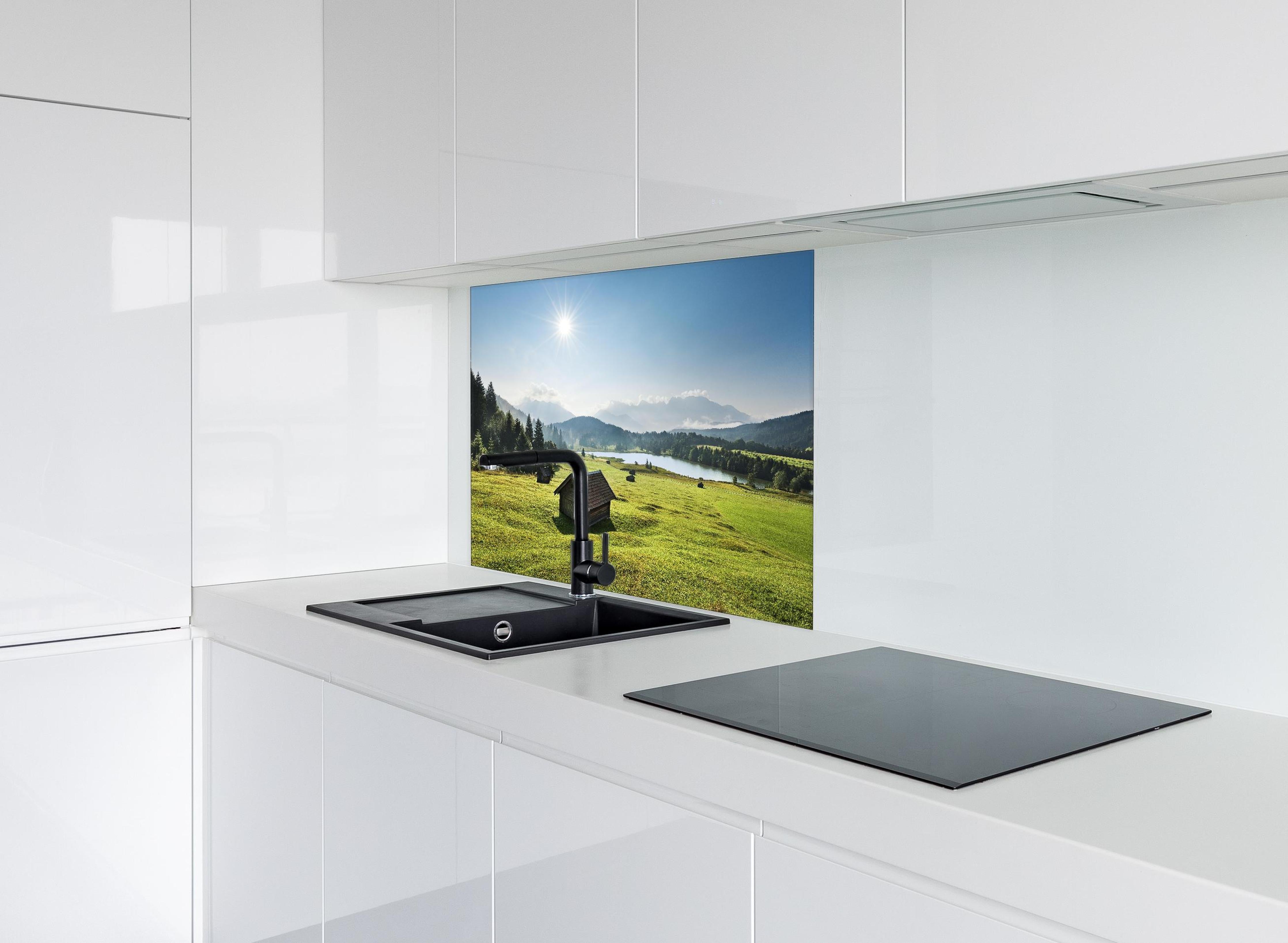 Spritzschutz - Grüne Alpenwiese, Berge und See im Sonnenschein hinter einem Cerankochfeld zwischen Holz-Kochutensilien