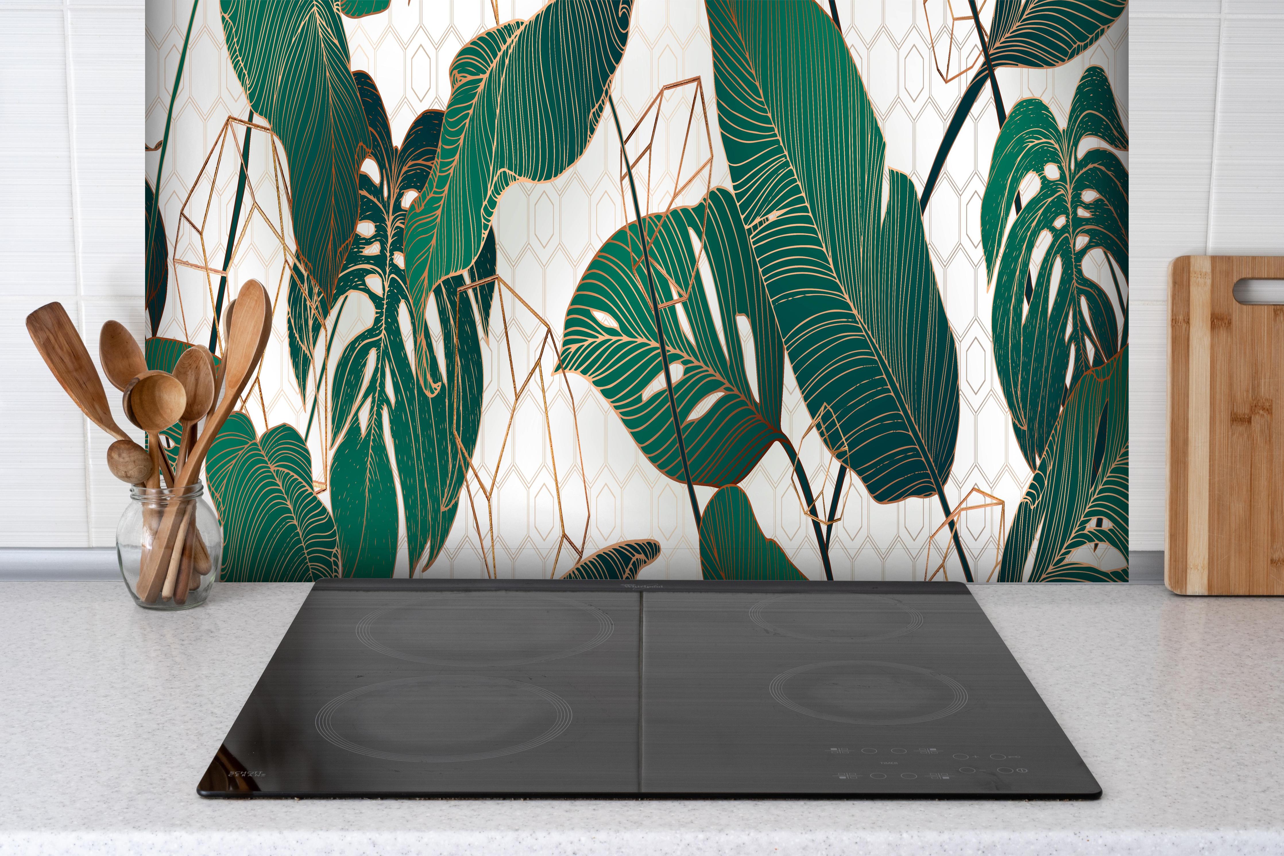 Spritzschutz - Grüne Blätter auf eleganter Tapete hinter einem Cerankochfeld zwischen Holz-Kochutensilien