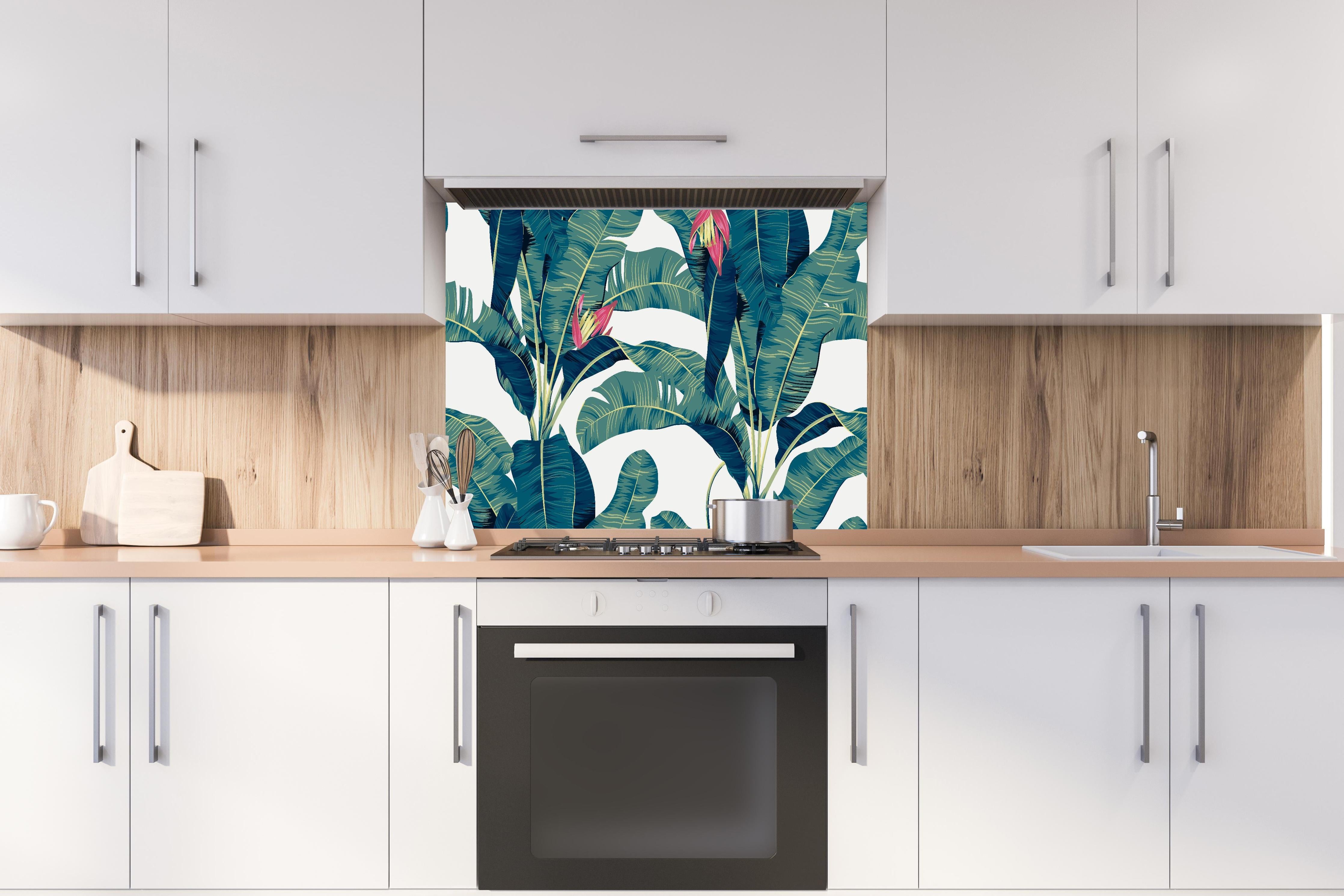 Spritzschutz - Grüne Exotische Bananenblätter Illustration hinter einem Cerankochfeld zwischen Holz-Kochutensilien